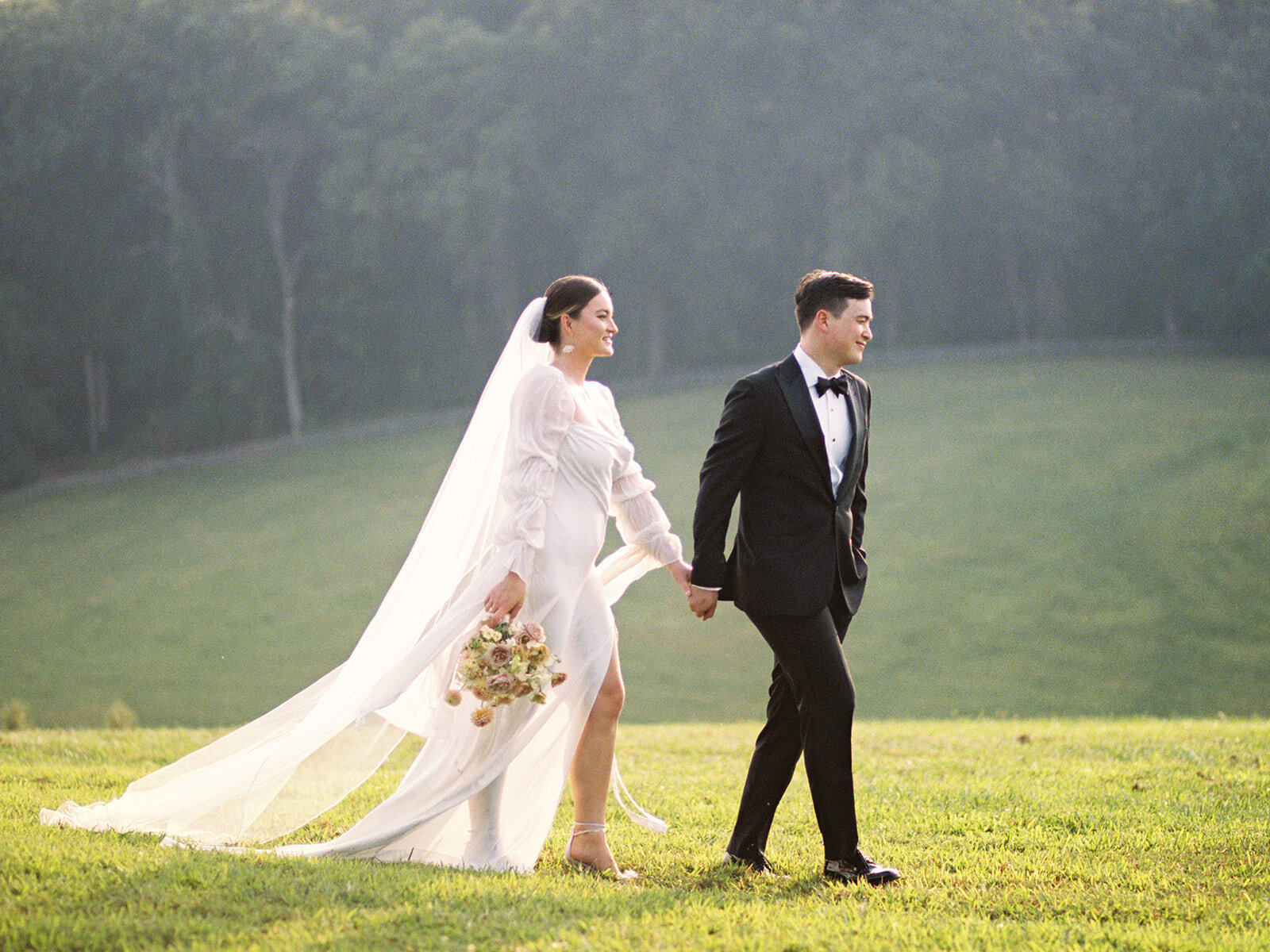 Portrait of bride and groom walking along pastures at the Harford Hills wedding venue in Fallston Maryland rolling hills