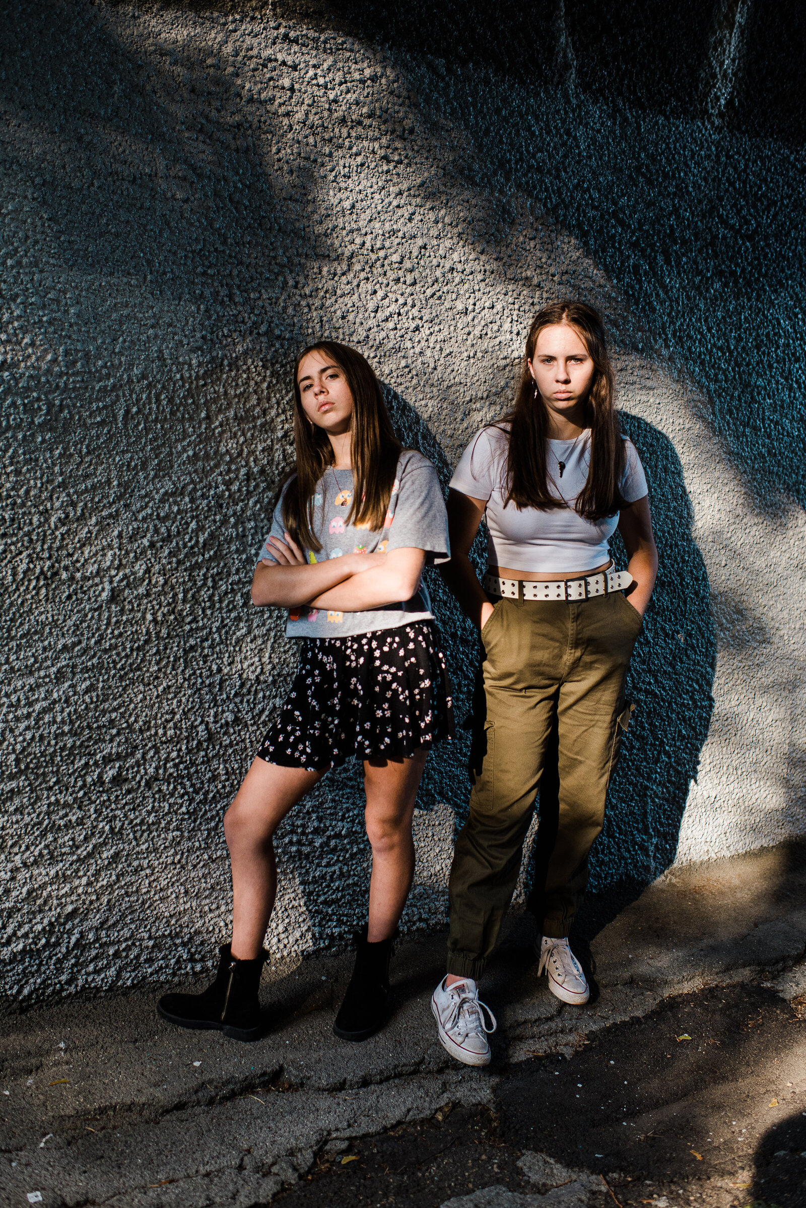 girls serious in dramatic light in front of stone wall