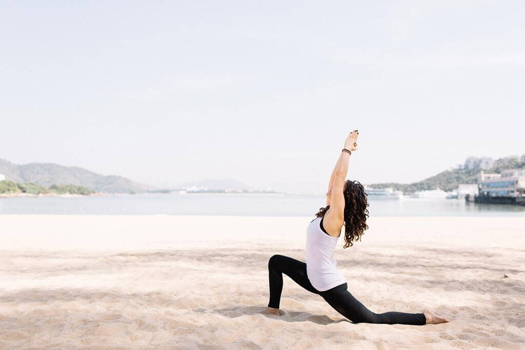 Outdoor branding yoga session of a women doing yoga in the sand.