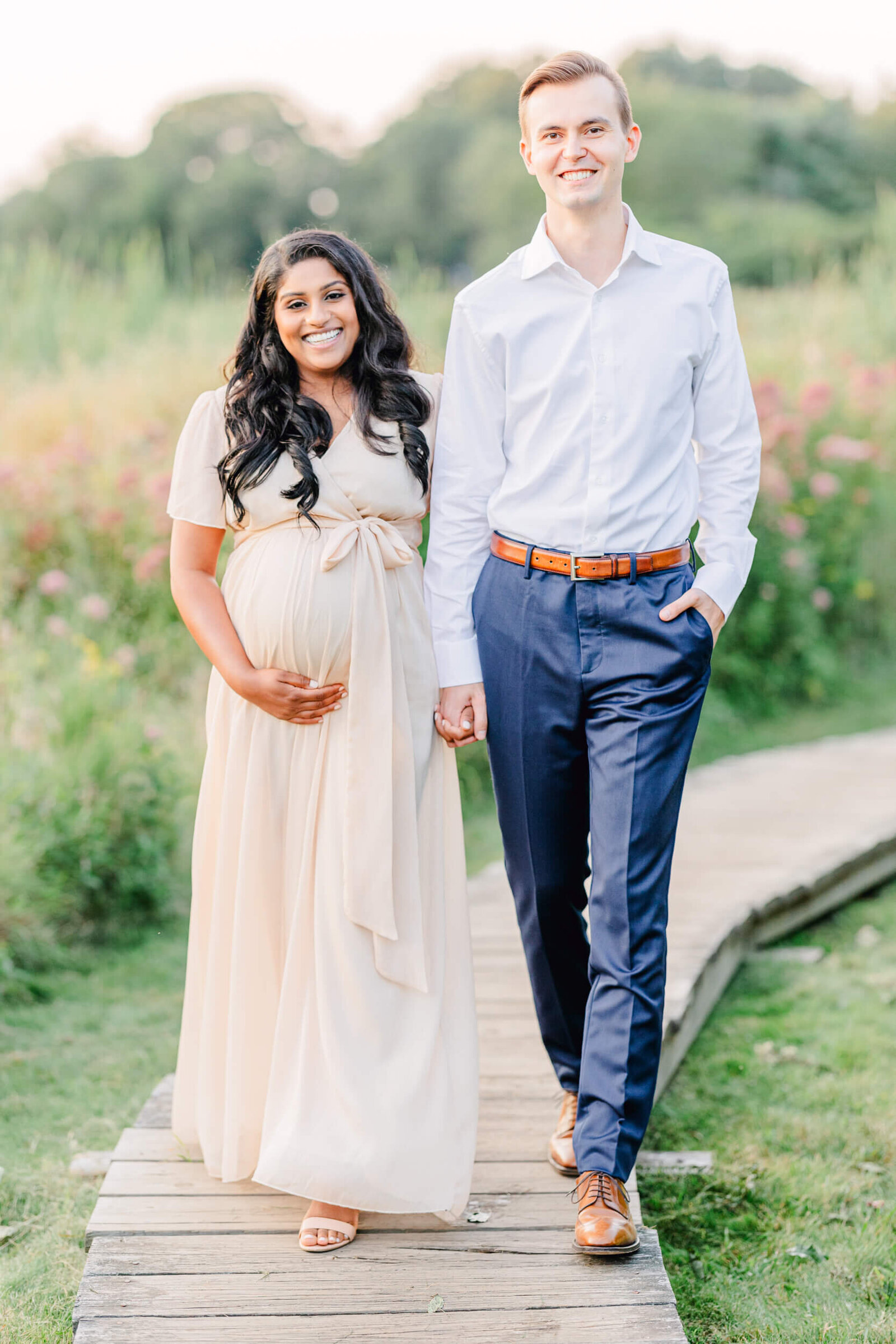 Pregnant woman and her husband smiling, holding hands, and walking