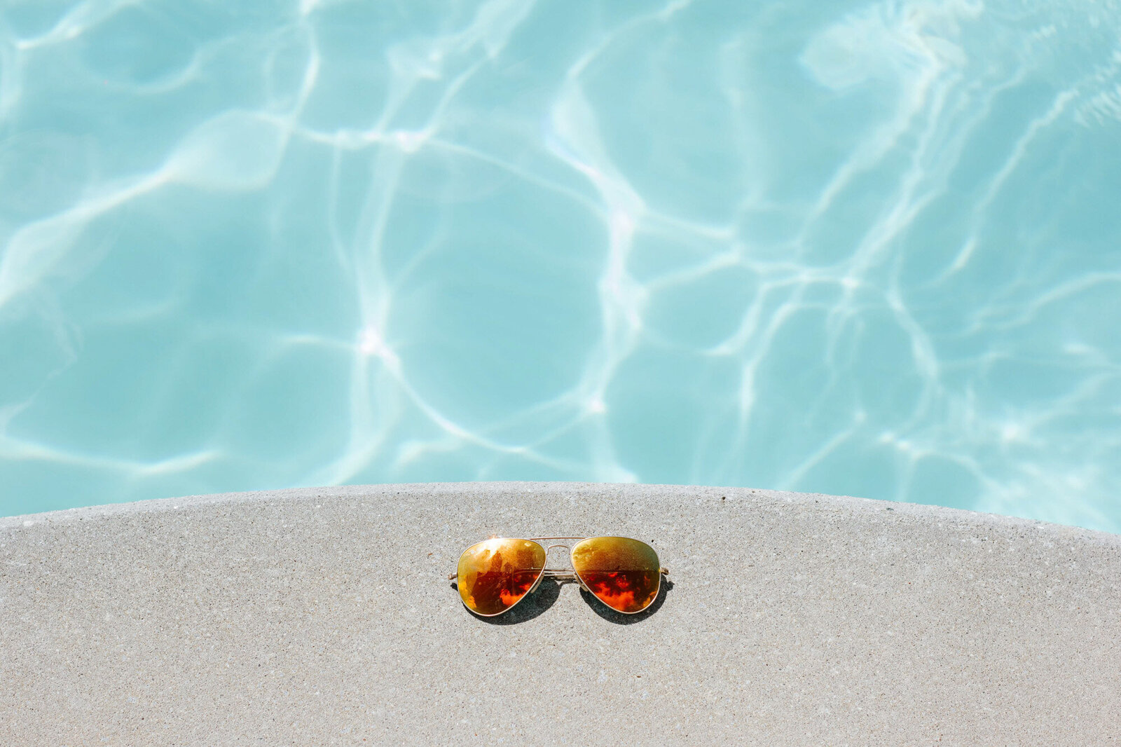 Photo of a sunglasses that is beside the pool