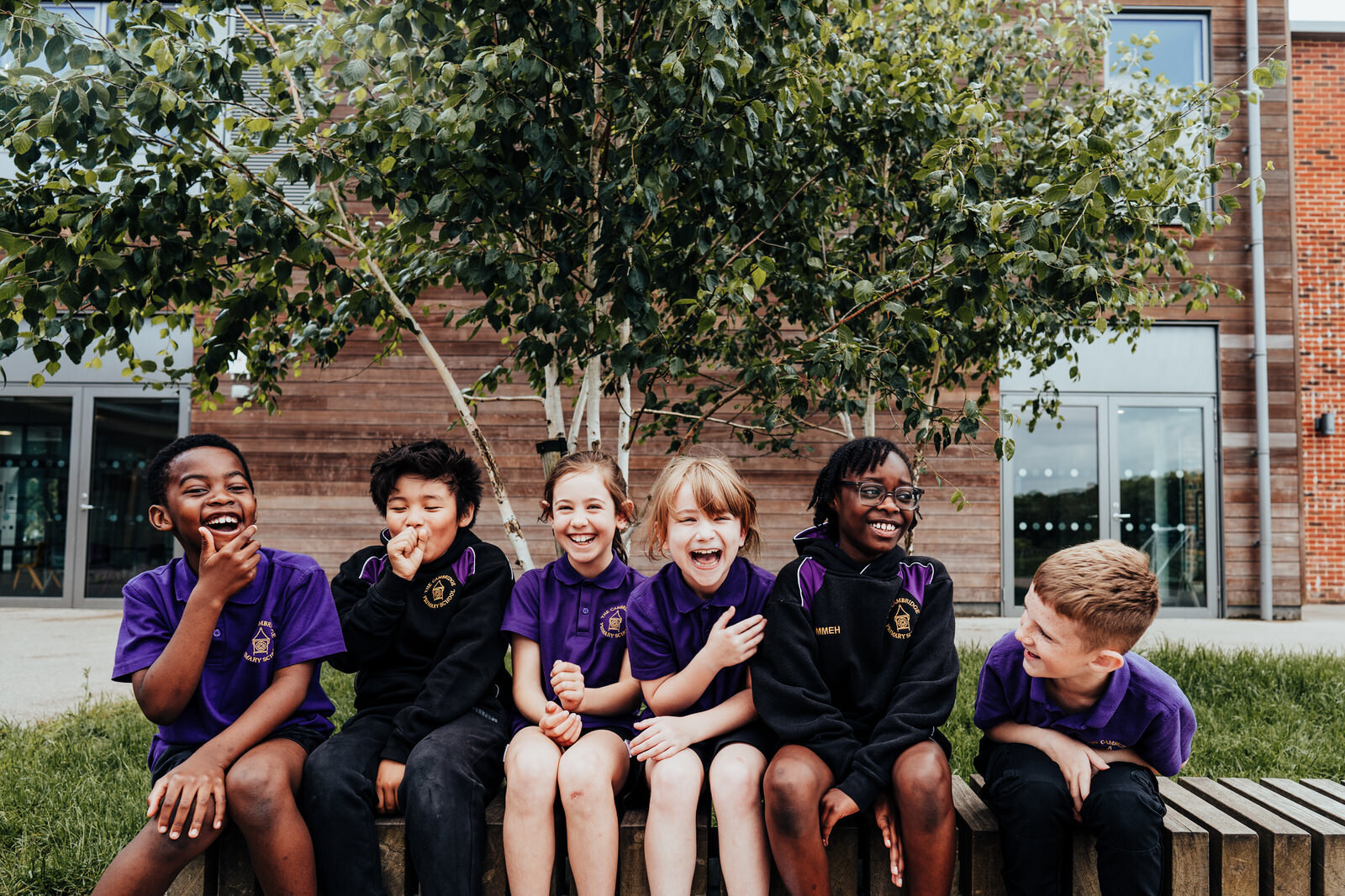 Students from The Cambridge Primary School, sitting on bench outside classroom