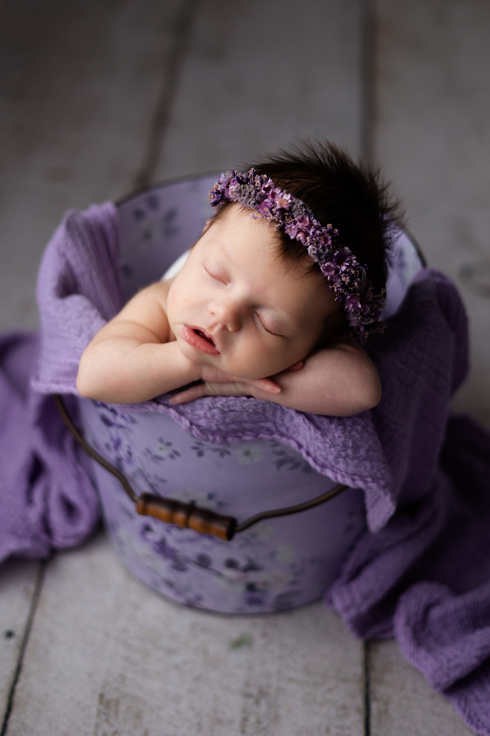 Baby girl with purple floral halo, posed in a  matching purple bucket