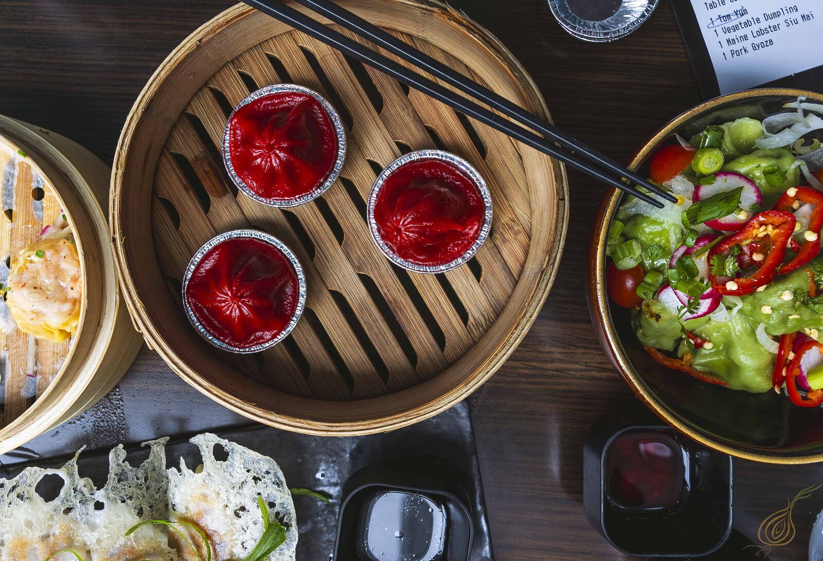 A dish of red dumplings and other dishes presented on a plate, with chopsticks placed next to the meal.