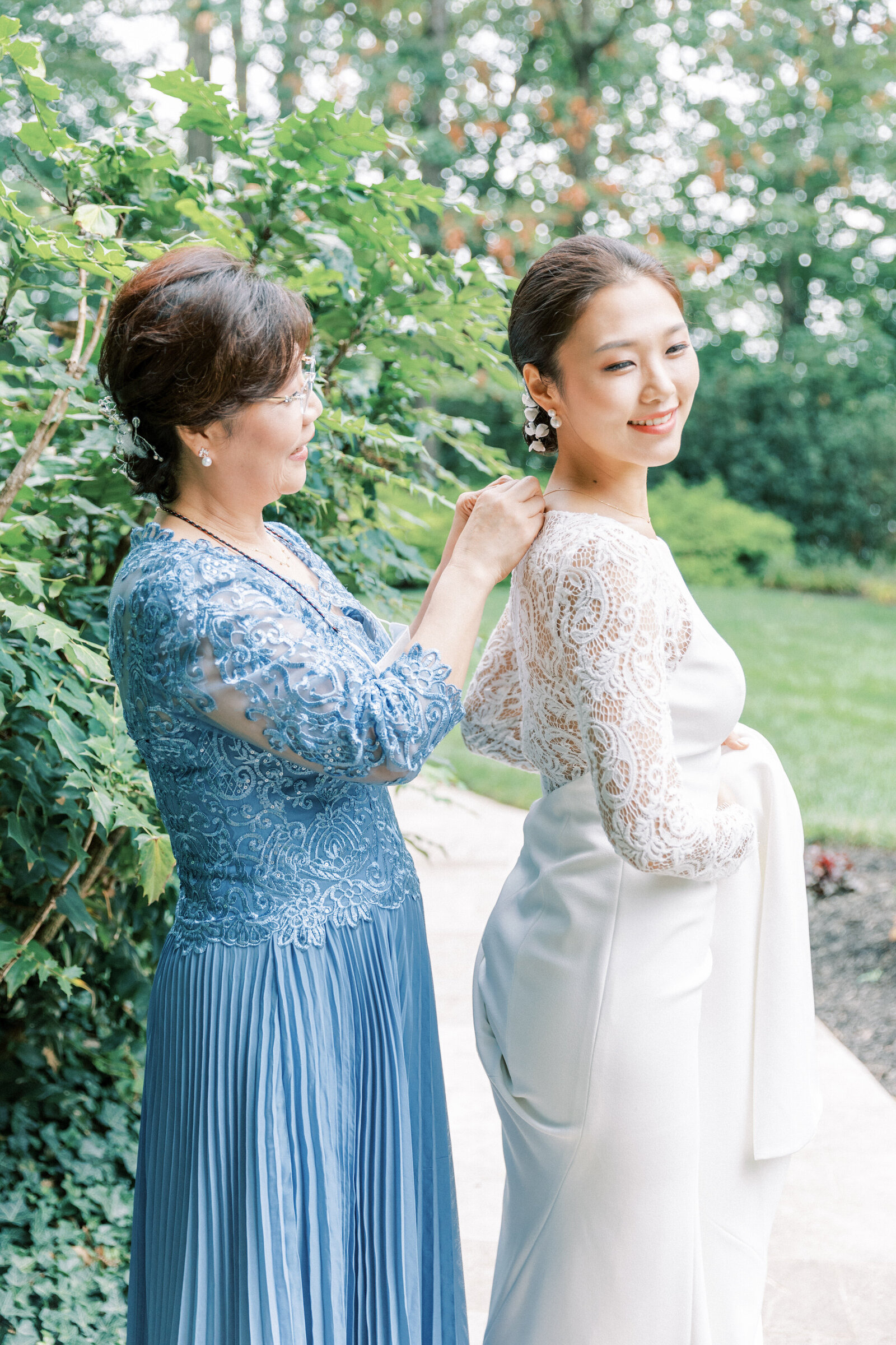 Bride has dress buttoned by her Korean mother