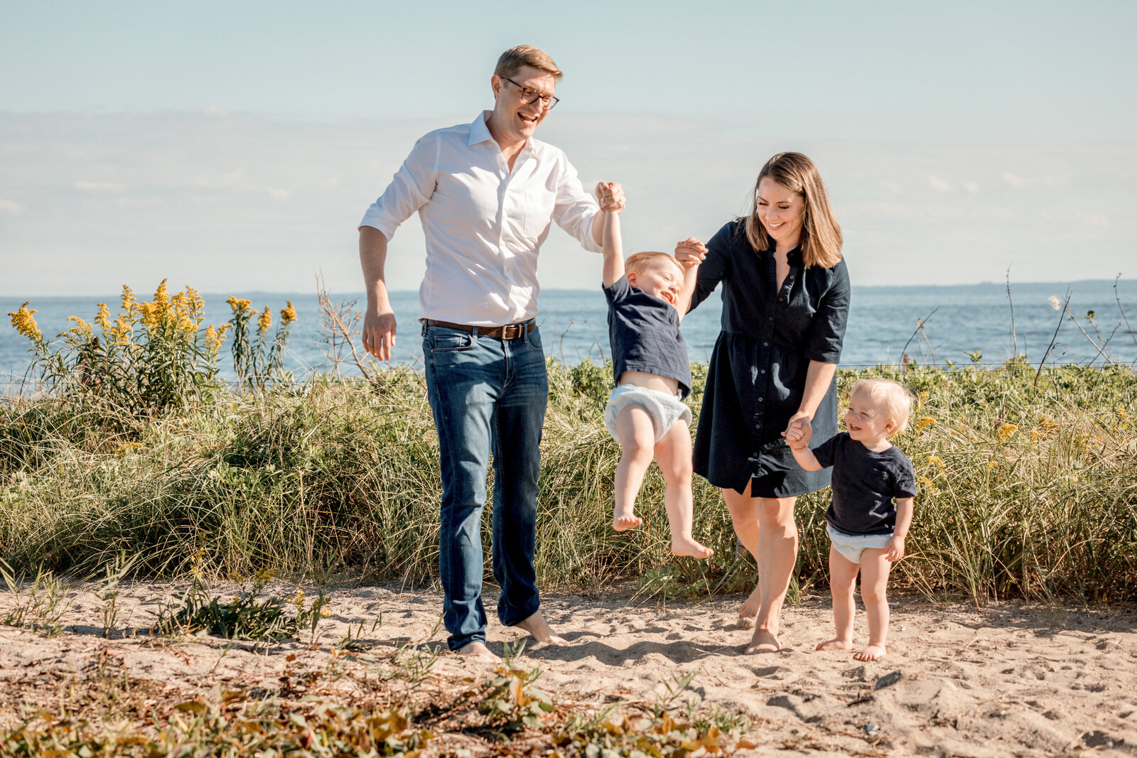 family swinging their son on the westport beach