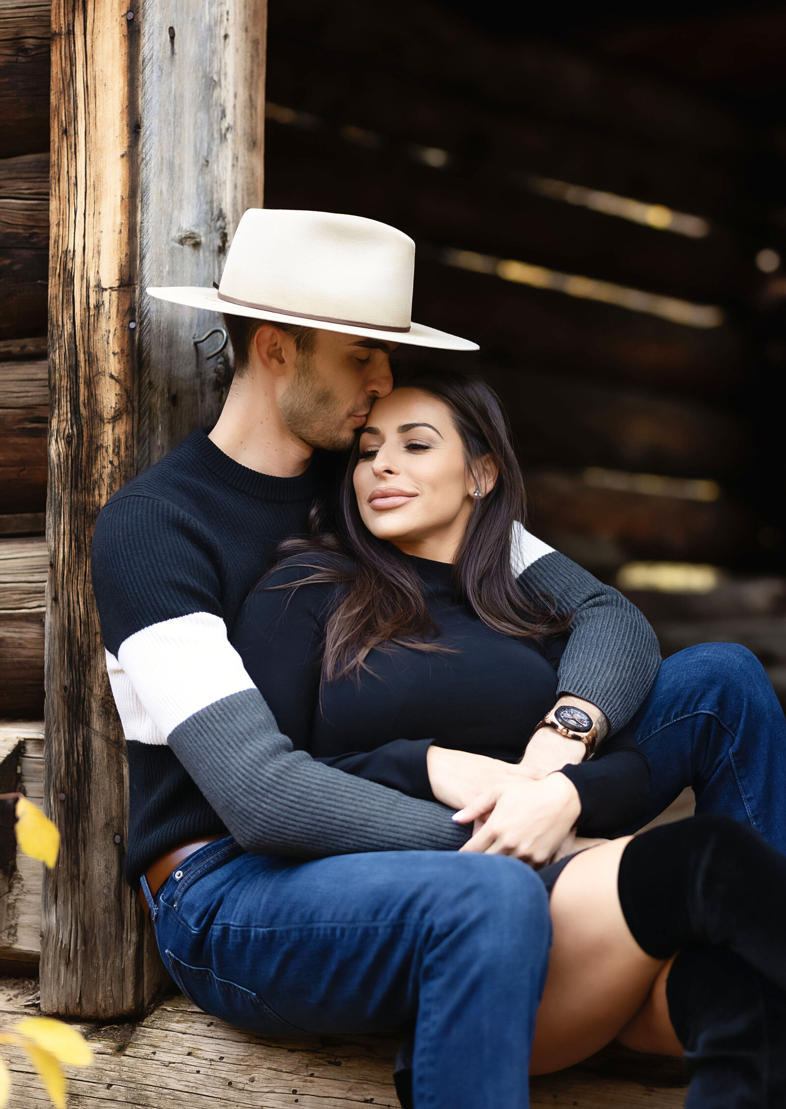 A sweet couple snuggle and kiss at Ashcroft Ghost Town in Aspen, Colorado during their engagement photoshoot.