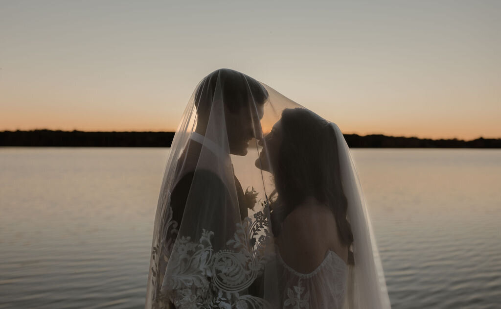a romantic wedding photo of the bride and groom by the water