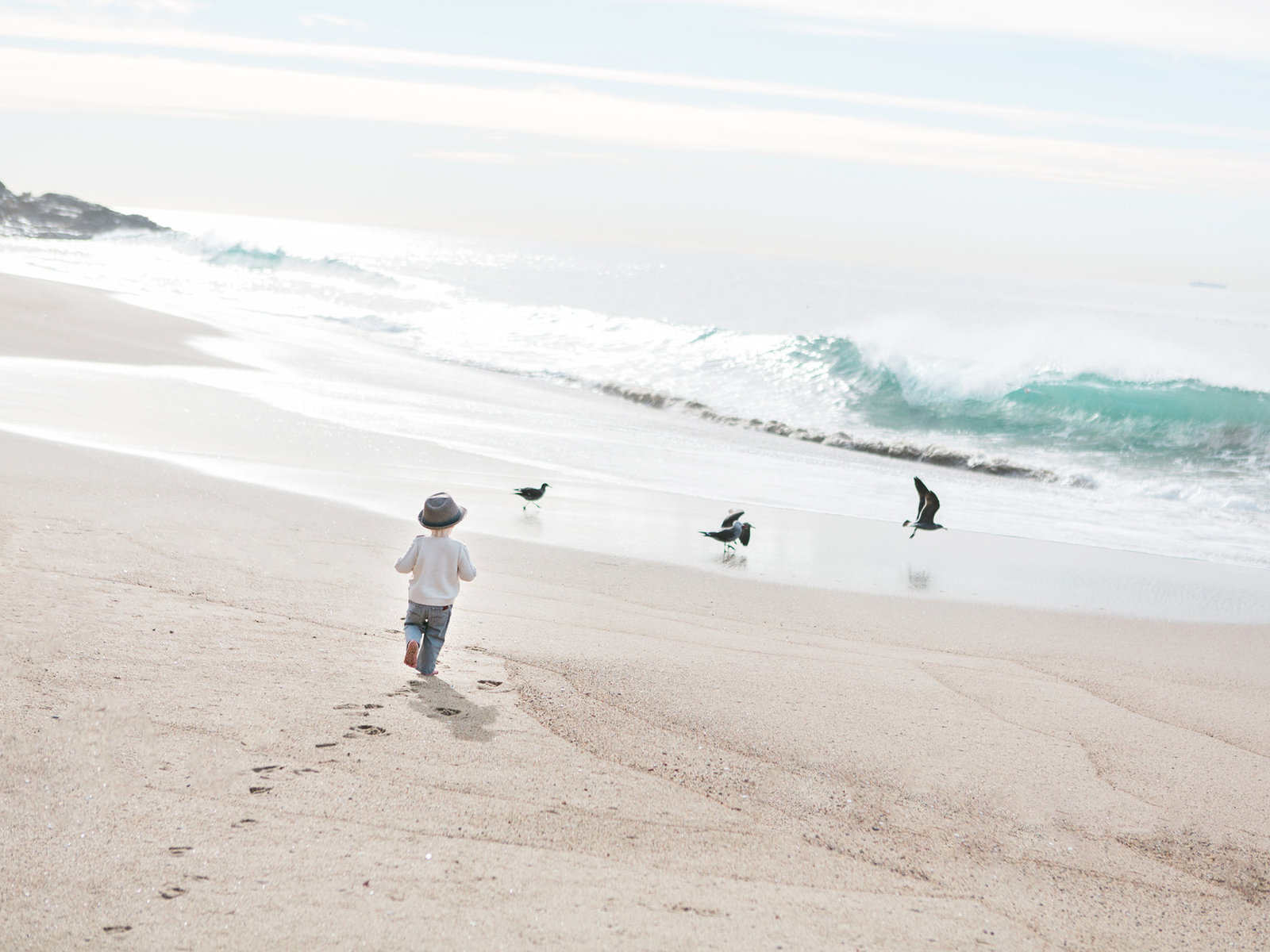 A boy runs along the surf during a family photo session in Ventura California