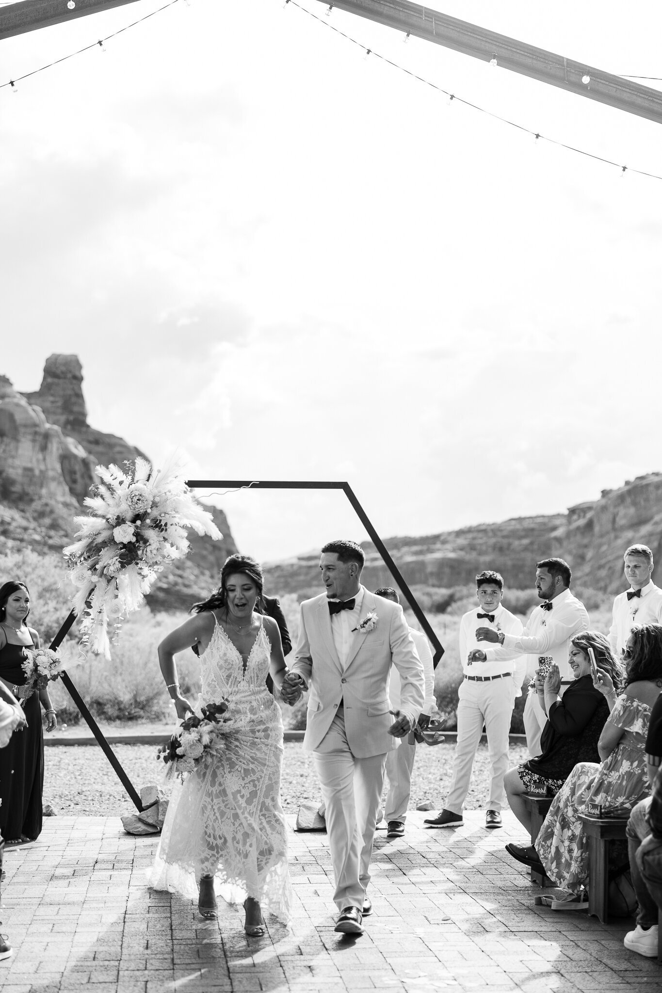 Black and white image of bride and groom walking down the aisle at their wedding in Moab, Utah