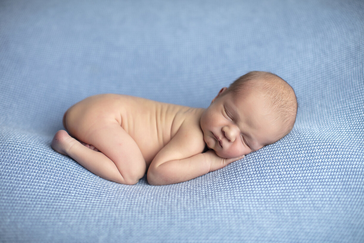 Newborn on blue fabric.