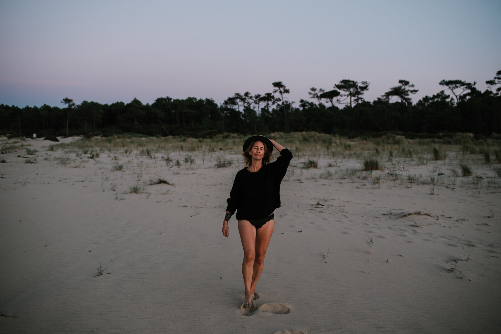 woman is walking on a sandy beach looking content and safe in her body