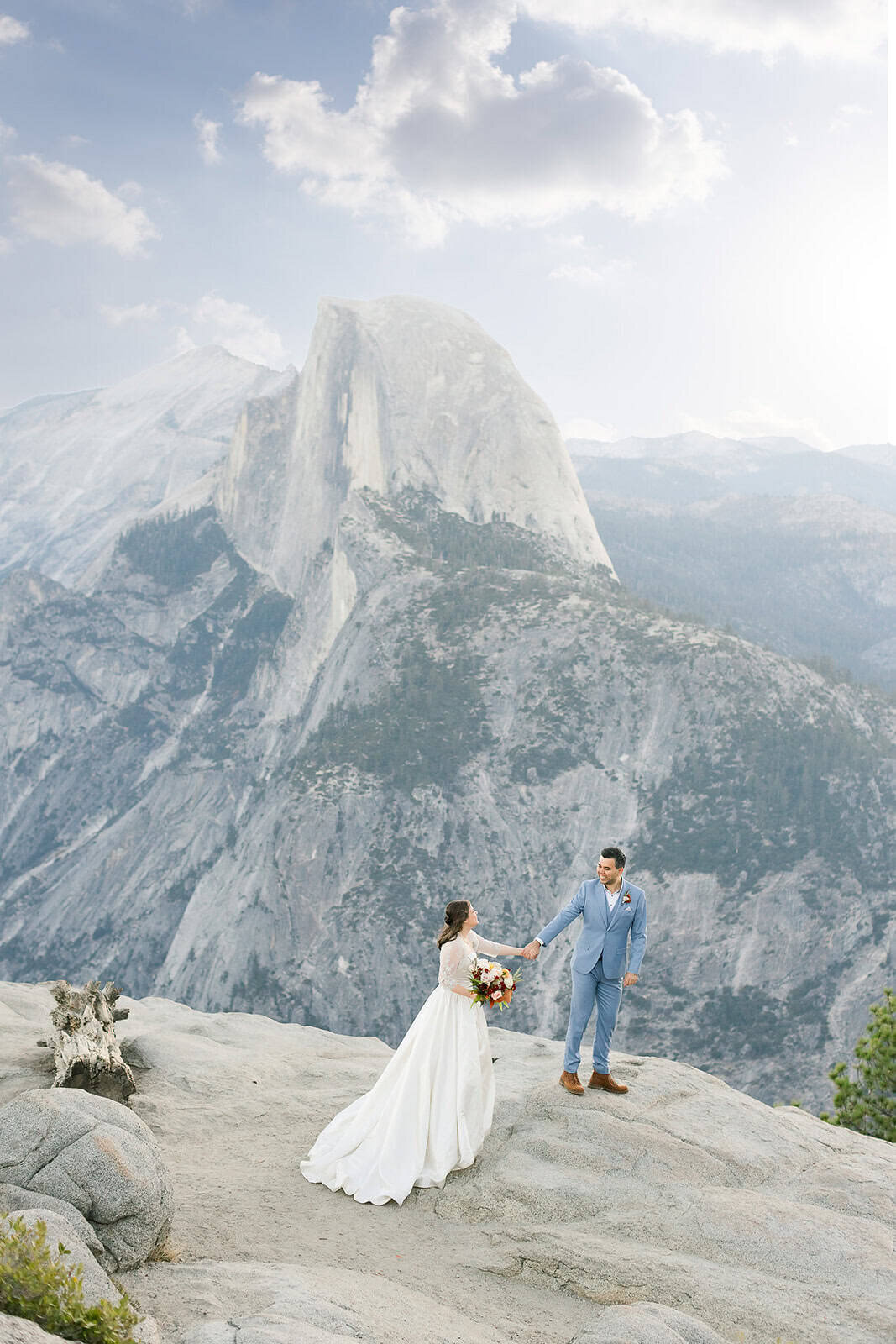 A couple enjoys their wedding day in front of the iconic half dome, from the view of Glacier Point in Yosemite National Park.