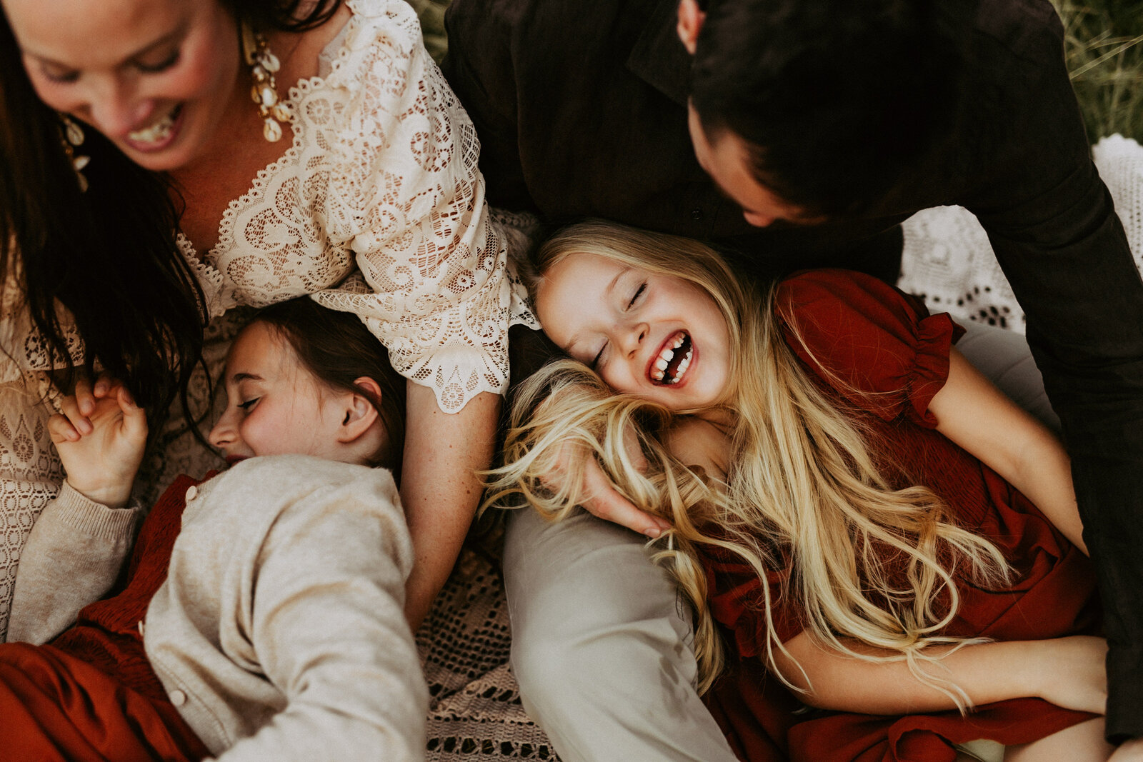en familj ligger på en filt utomhus och kittlas och kramas