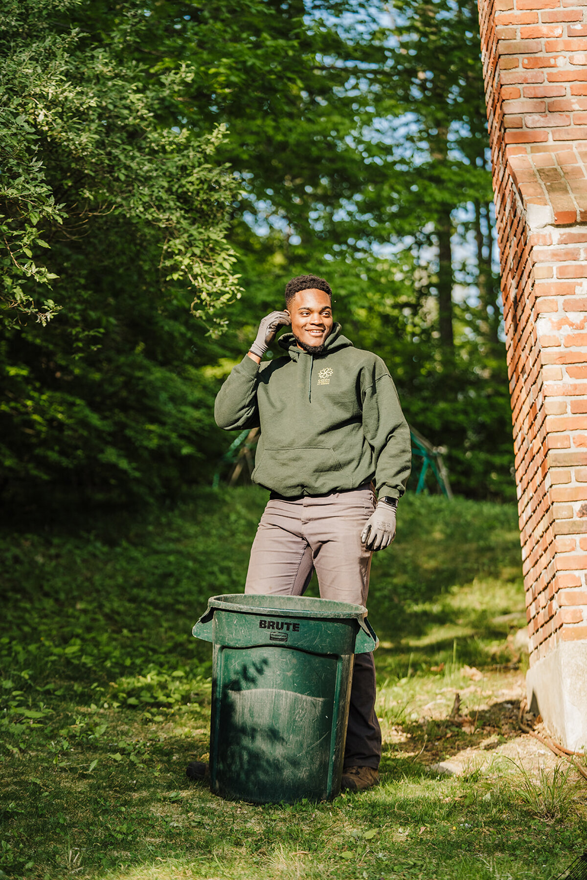 gardener in green sweatshirt works on a residential yard clean up