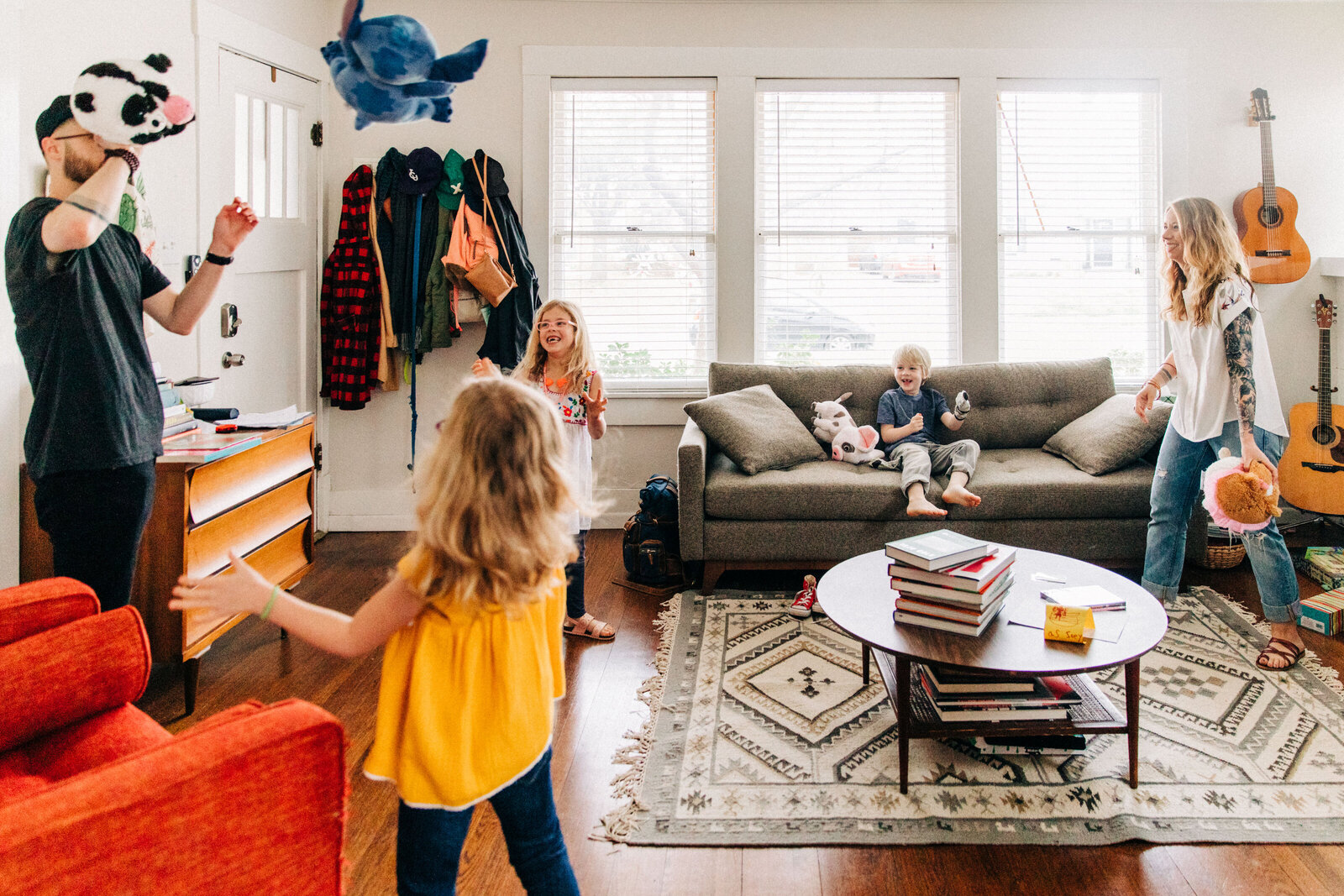family in their colorful mid century modern living room tossing a stuffed animal between them