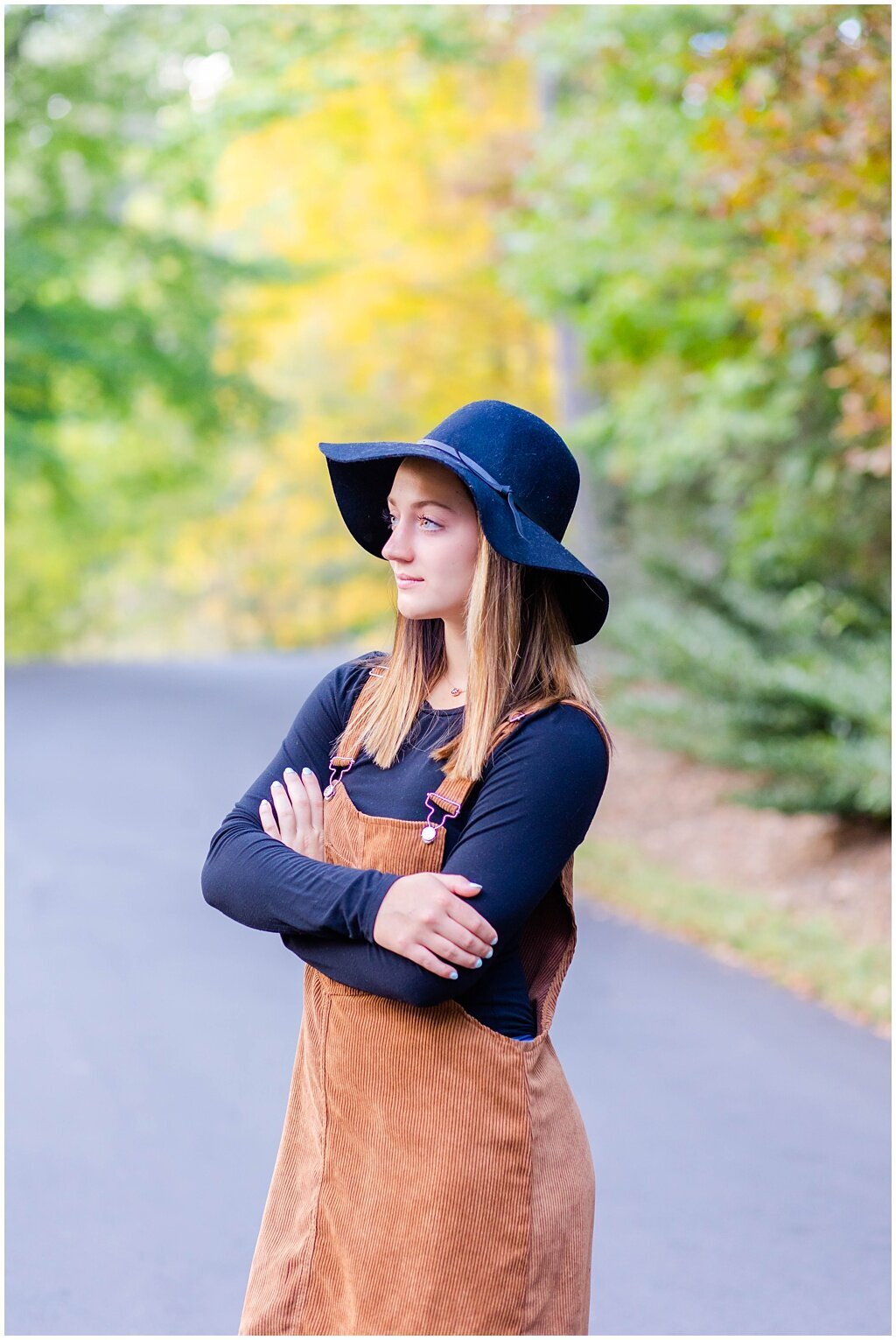 senior girl posing with fall outfit and black hat