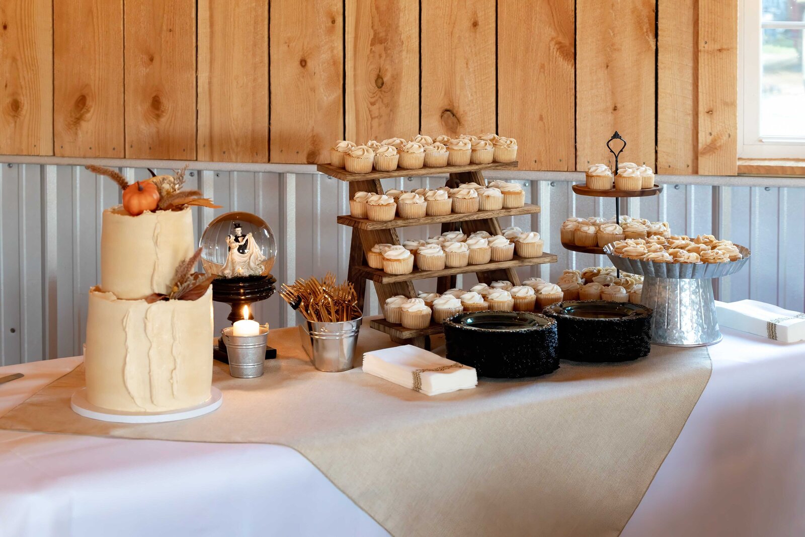 A beautifully decorated barn wedding reception table featuring burgundy napkins, a lantern centerpiece, and warm wood accents, captured at an Asheville, NC wedding, blending rustic charm with high-end elegance.