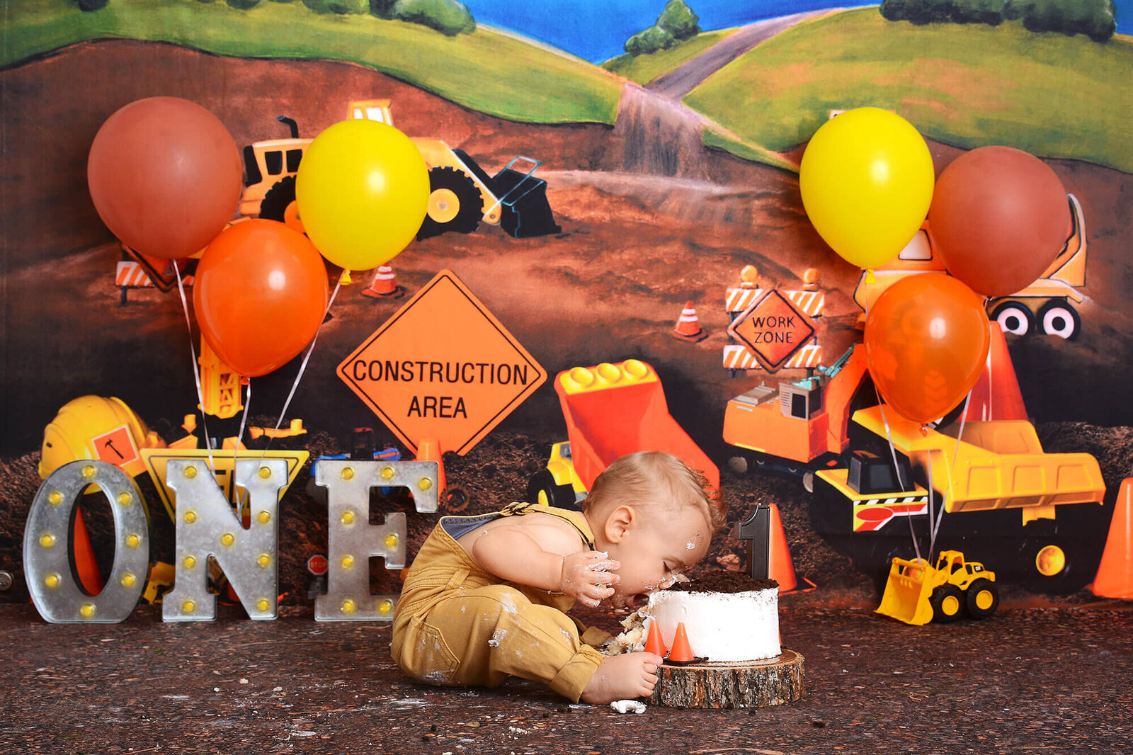 boy leans downs to bite into his smash cake at his cake smash photography shoot