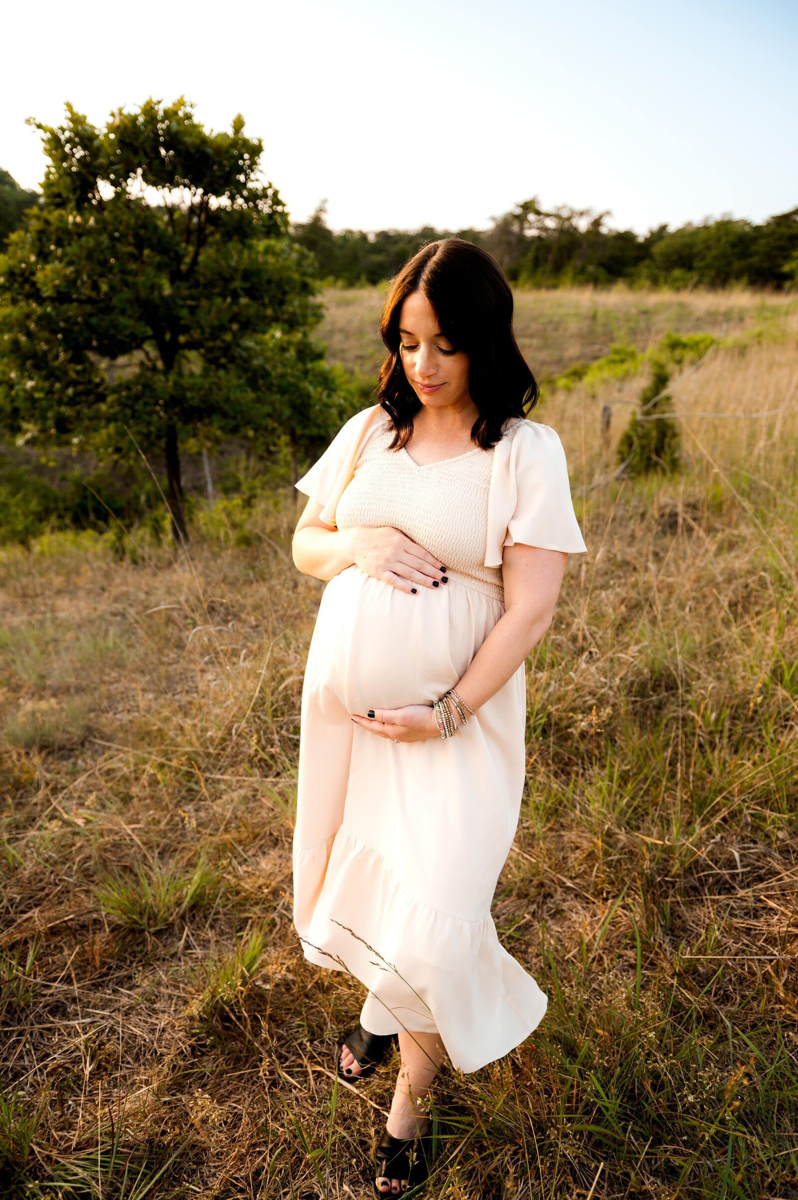 woman holding her pregnant belly in a field