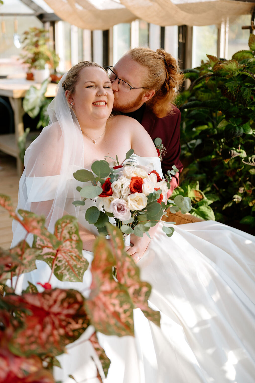 Bride giggling while being kissed by the groom