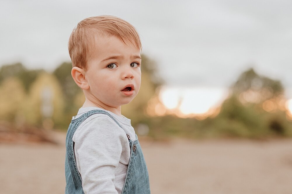 Toddler boy looking back at the camera on the beach with Vancouver Family Photographer