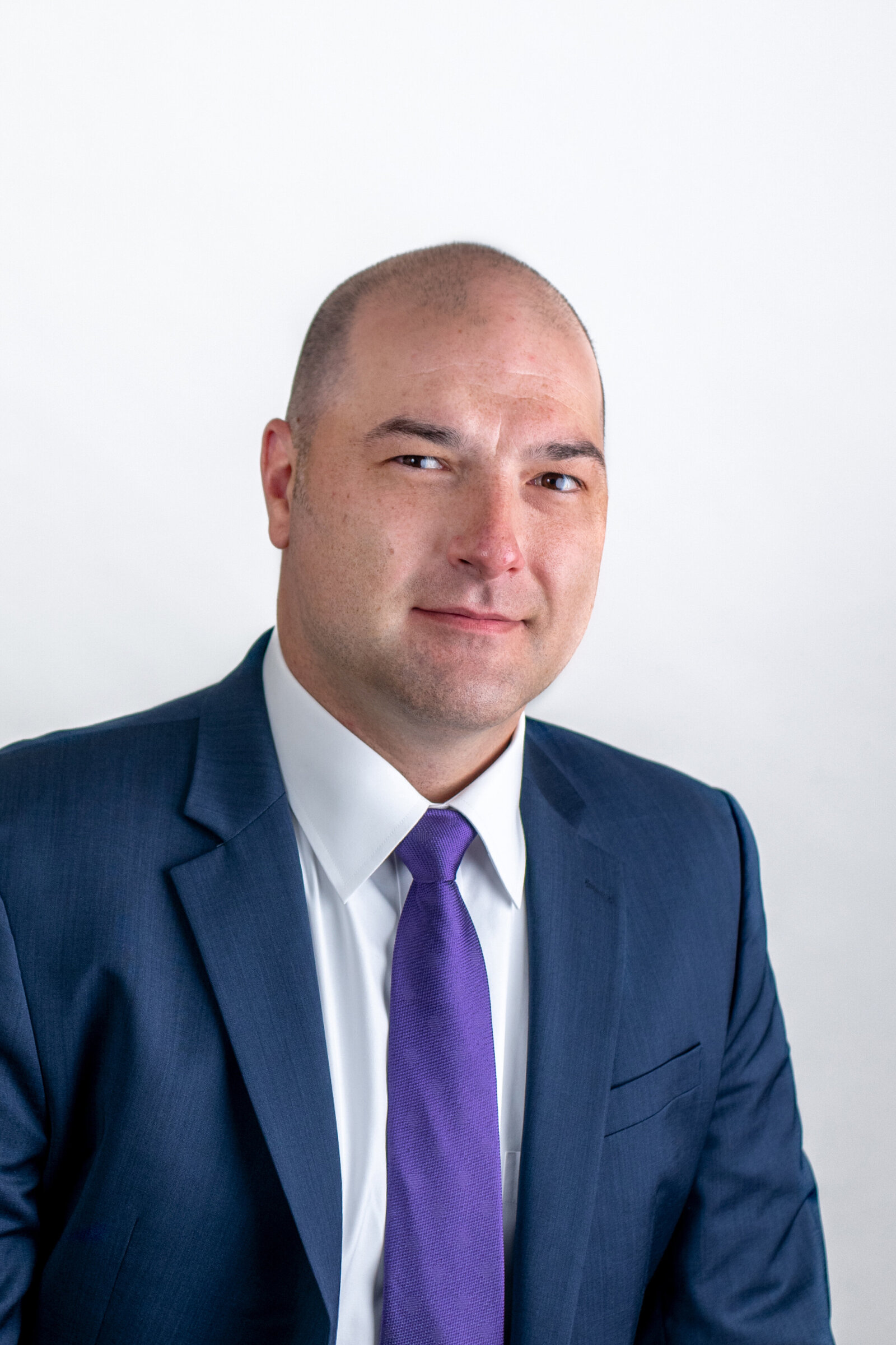 man wears suit and tie in business headshot on white backdrop