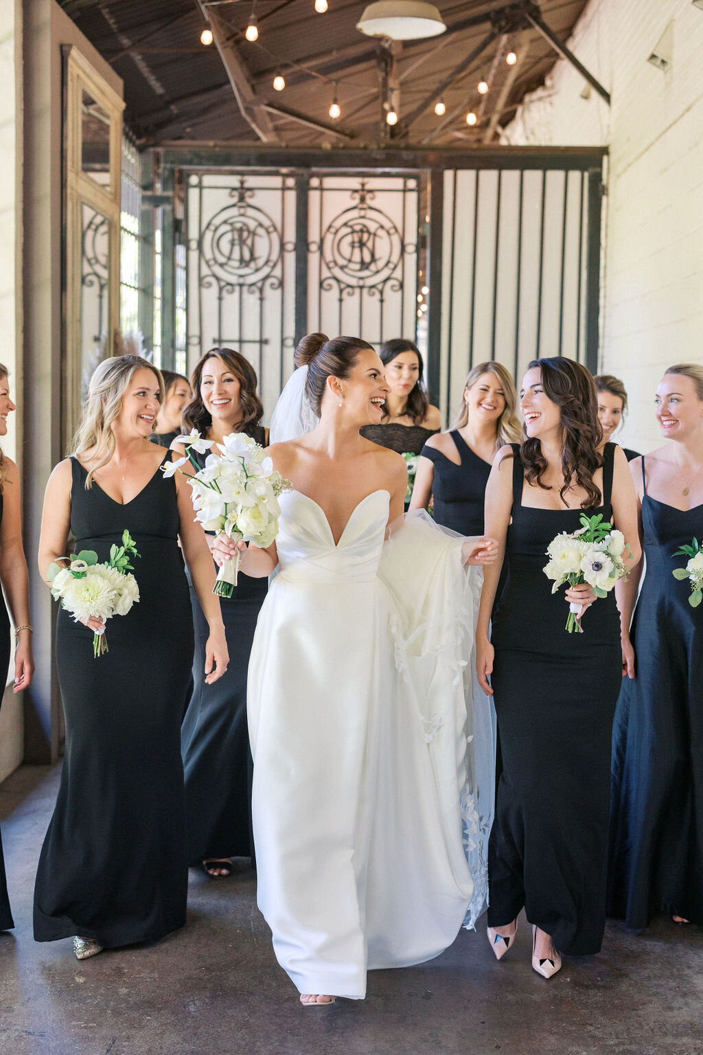 Bride smiles with bridesmaids wearing black dresses at the Westside Warehouse in Georgia