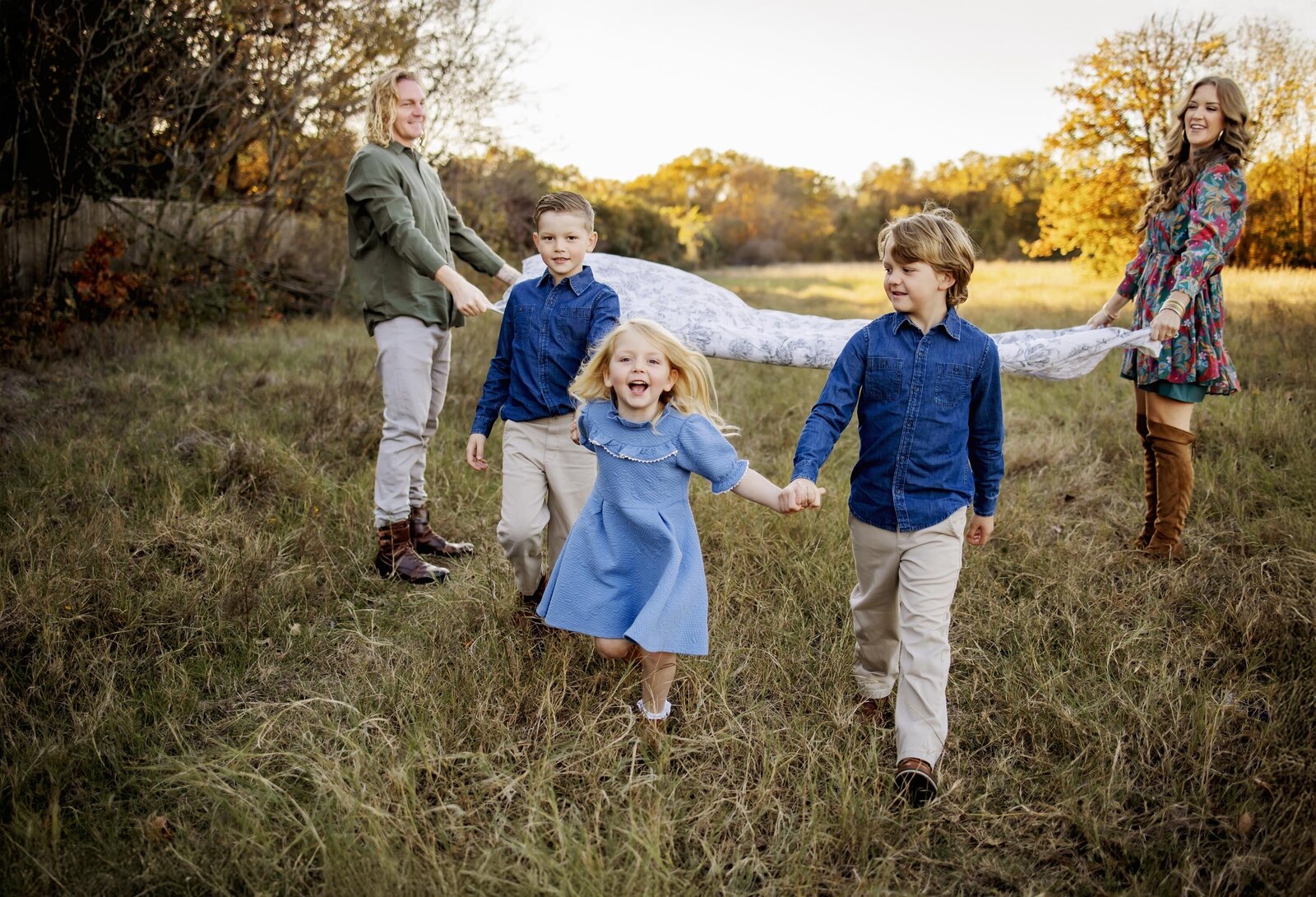 a family of 5 running in a field at a session in flower mound