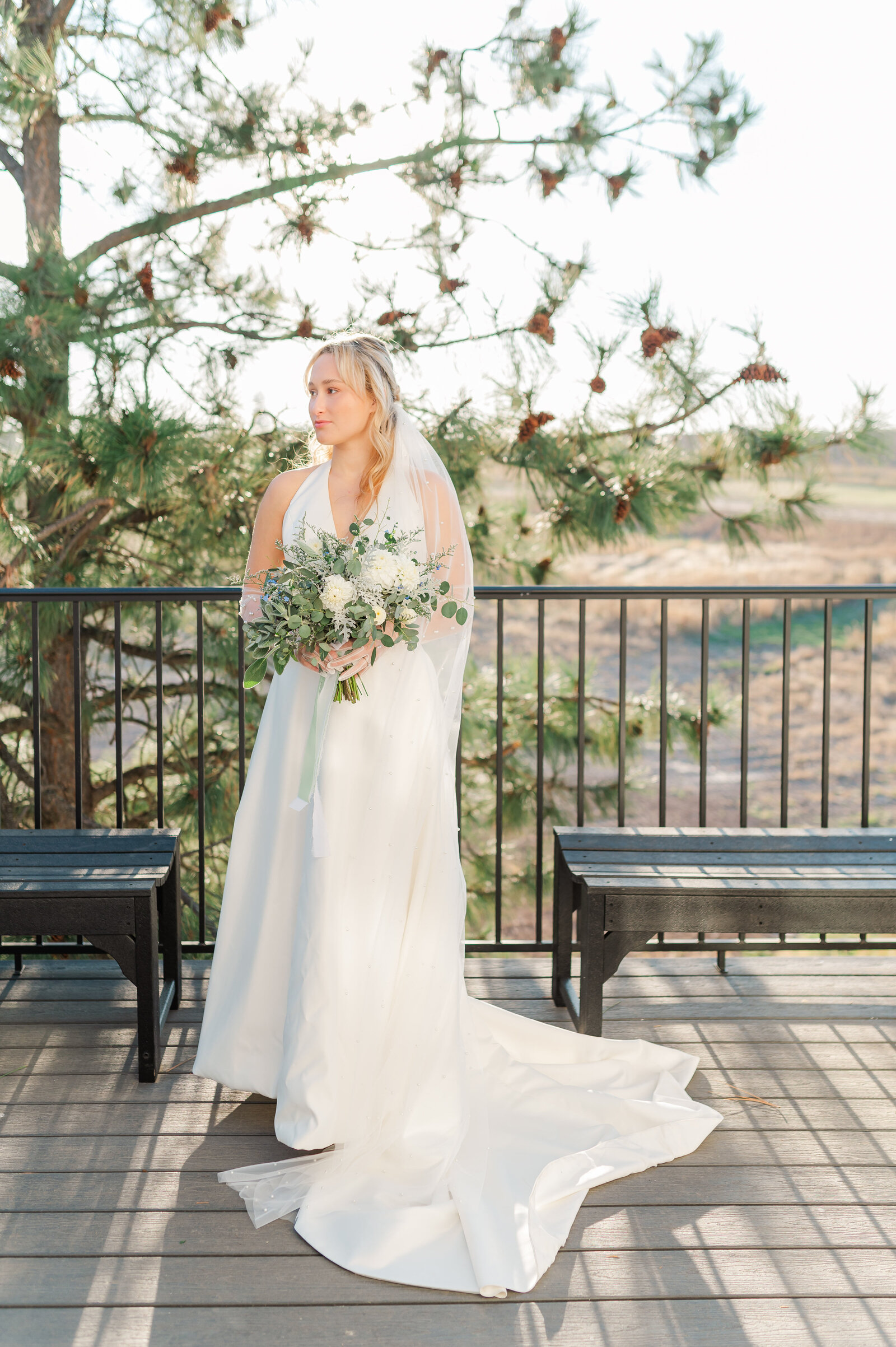bride standing on balcony in her dress at idaho wedding venue called edge of heaven weddings and events