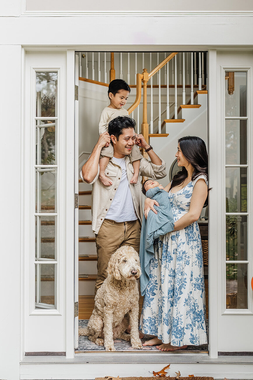 parents stand with sons and dog in doorway during boston newborn photos