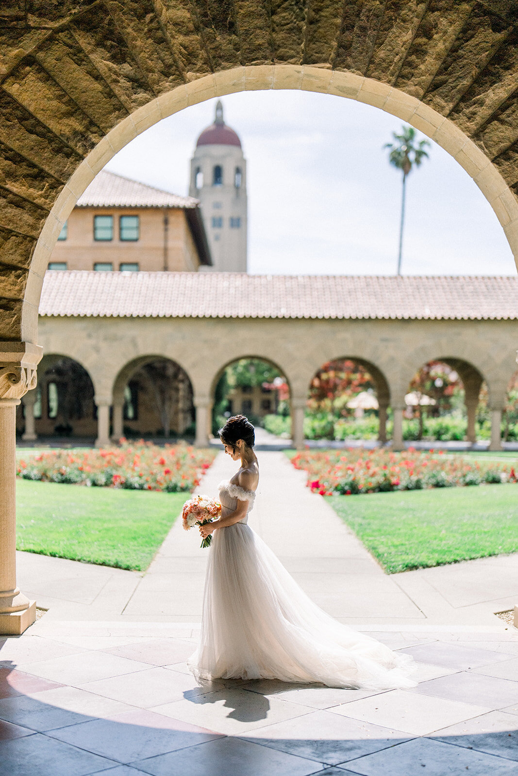 The bride gracefully walks through the historic arches of Stanford University, adding a touch of elegance to her wedding day.