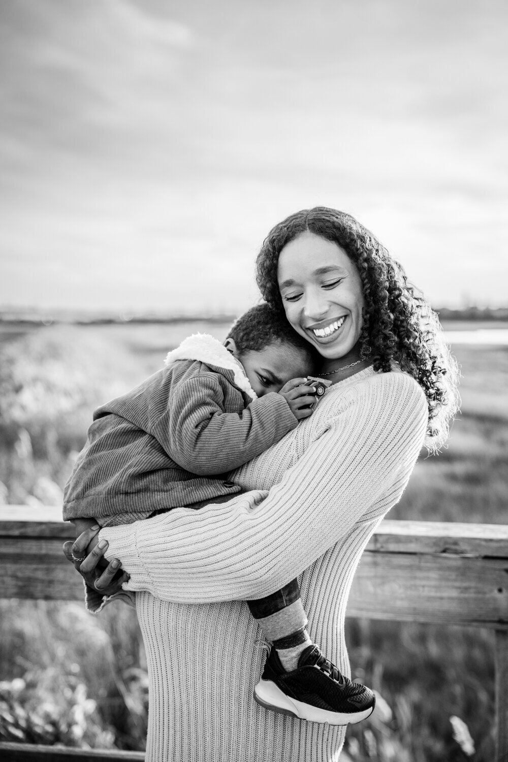 pregnant mom hugs little boy above belly in black and white maternity portrait