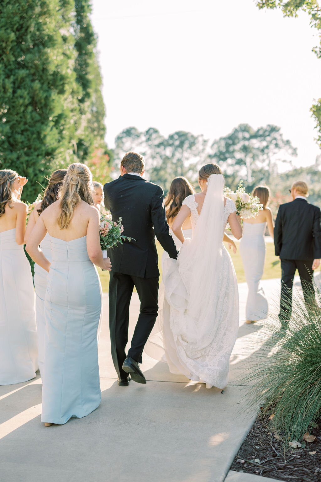 Bride and groom with wedding party walk to ceremony