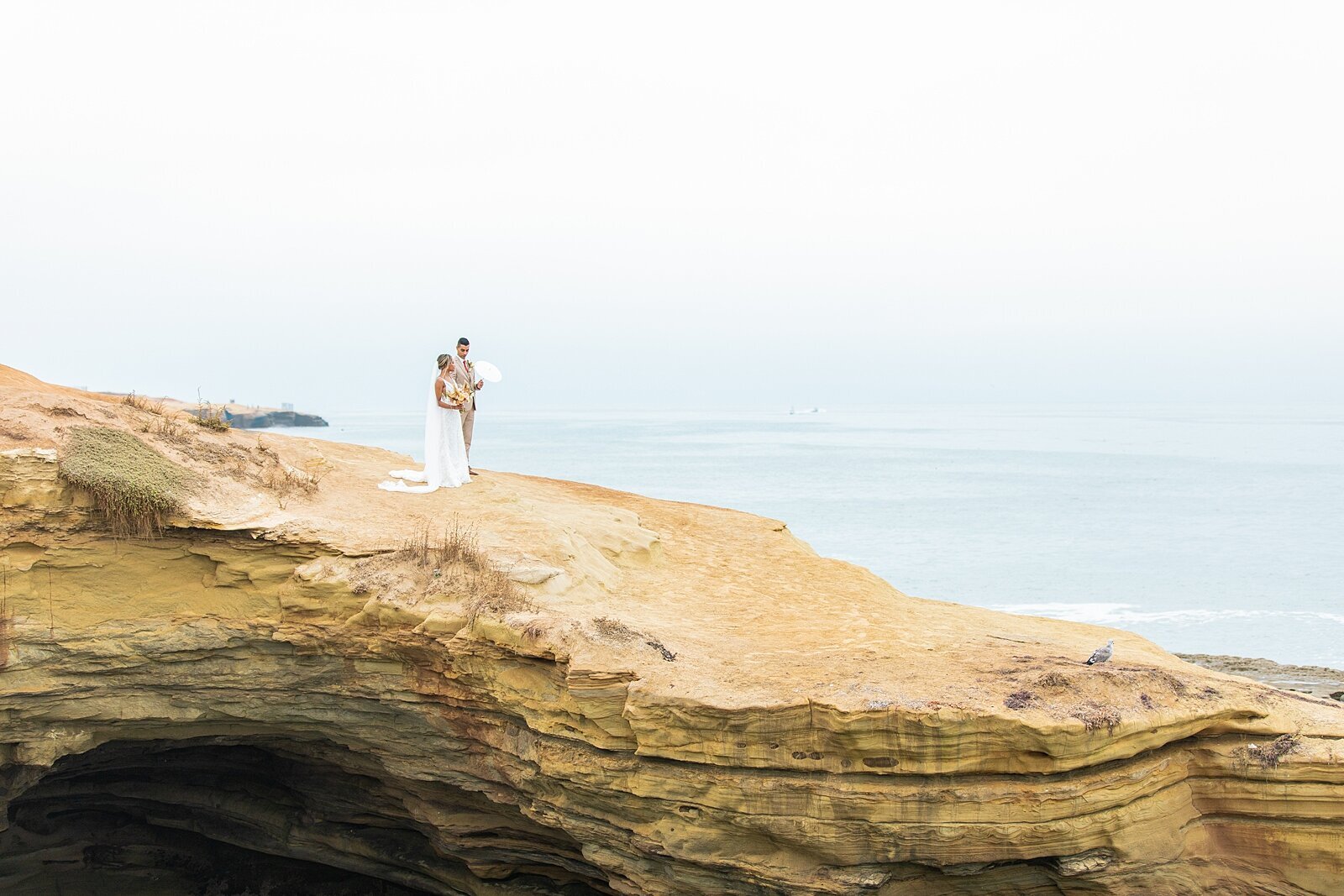 Bride and groom walking at Sunset Cliffs.