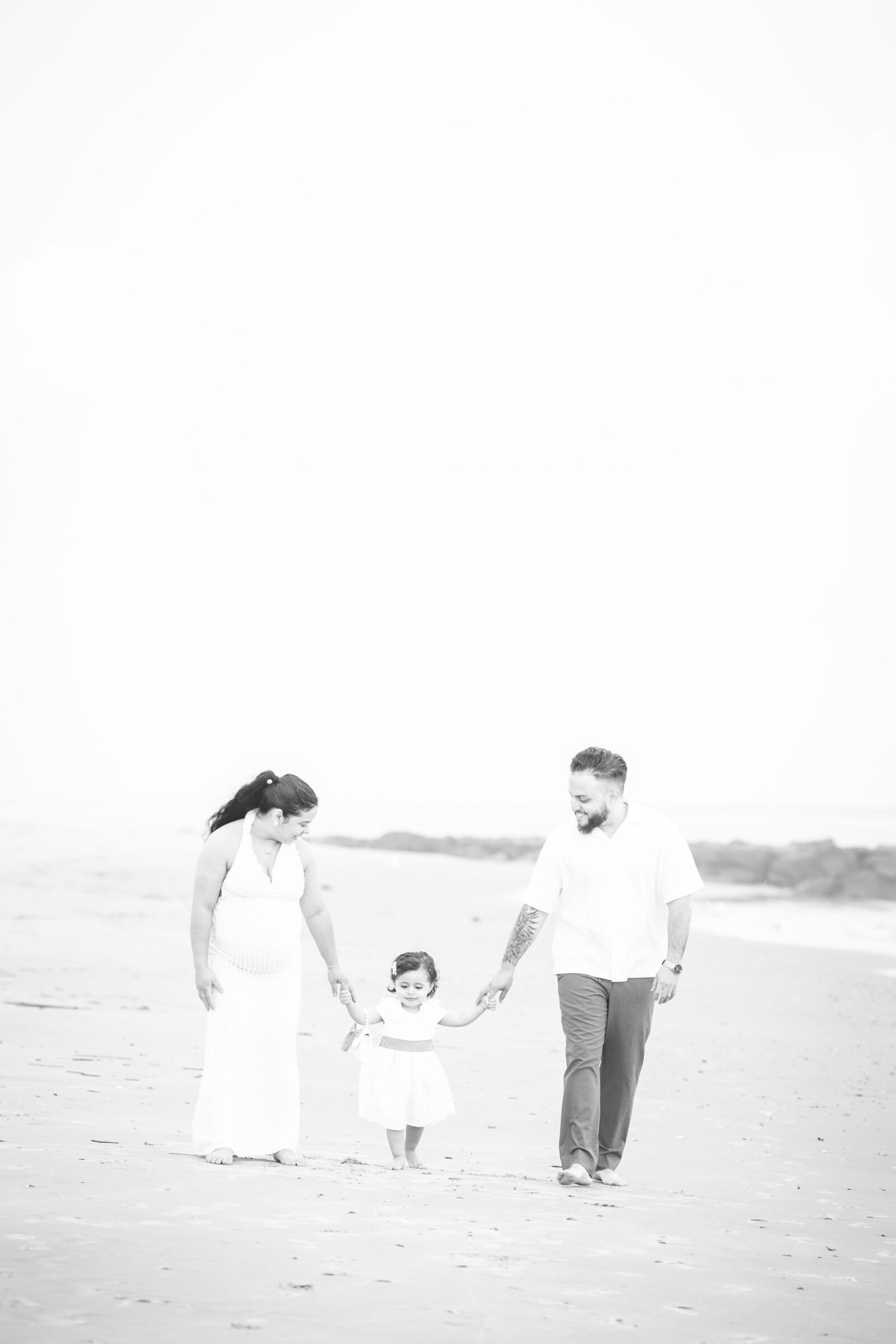 family of three parents walking with little girl on ocean city beach photographed by ally kimpton