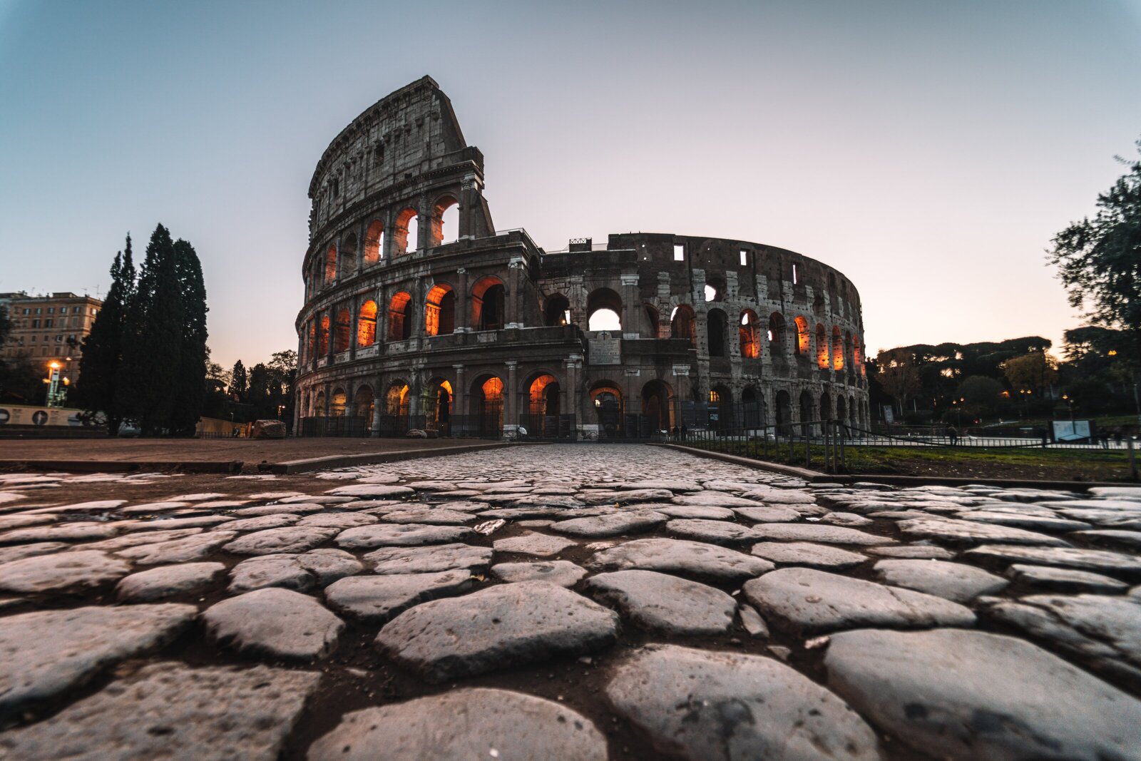 Ancient stone pathway leading to Rome Colosseum illuminated at dusk