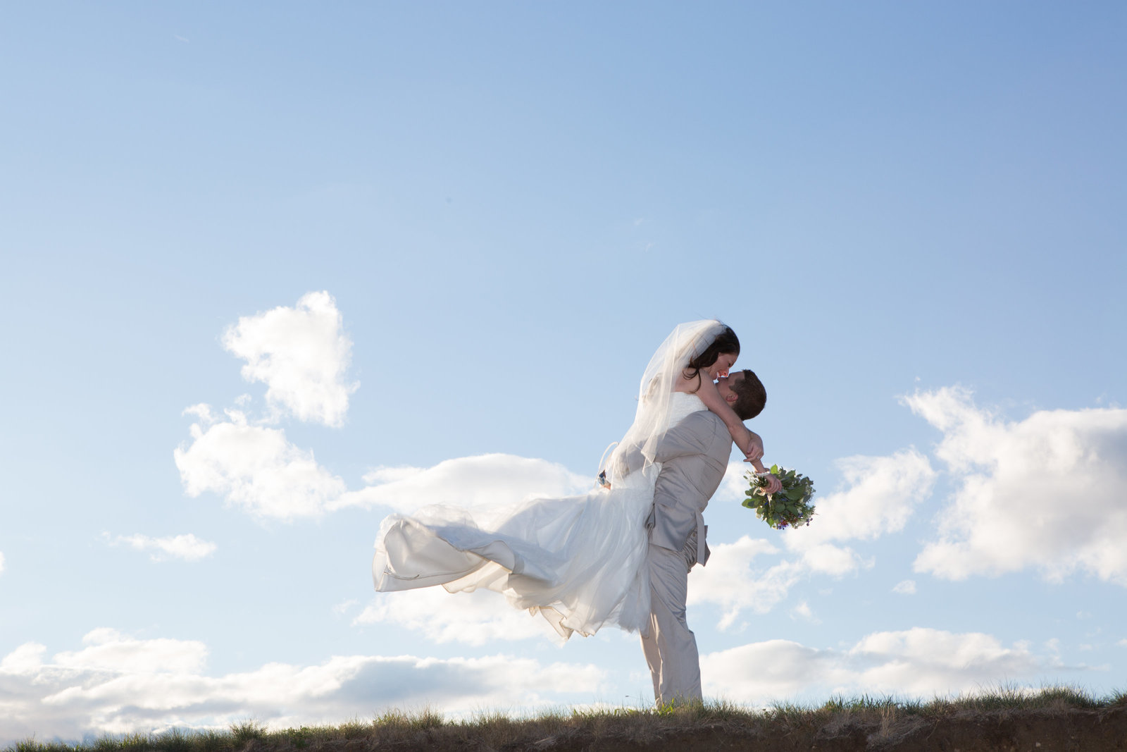 Groom lifting bride into air during wedding photo shoot