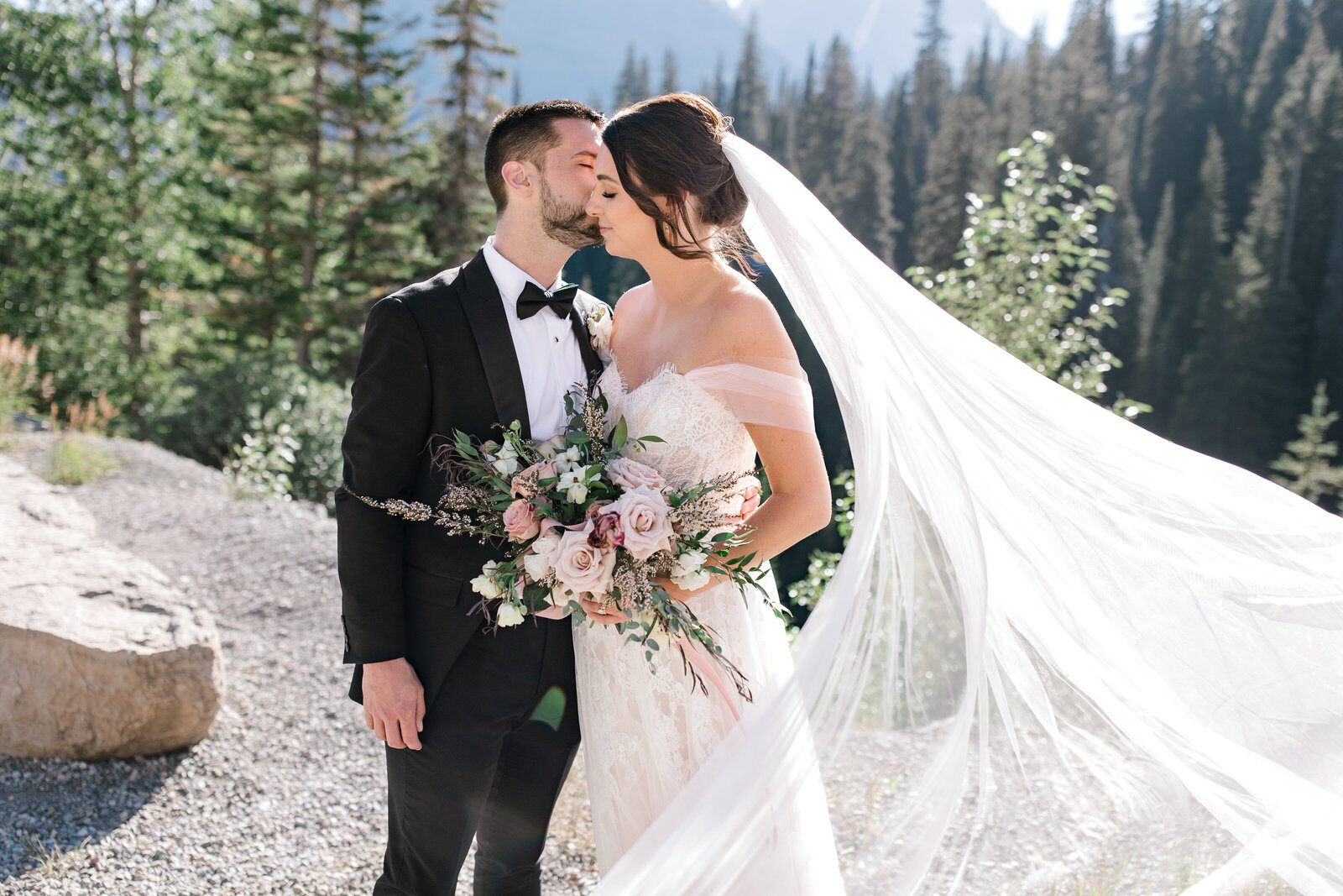 Bride and groom share a kiss on a mountain
