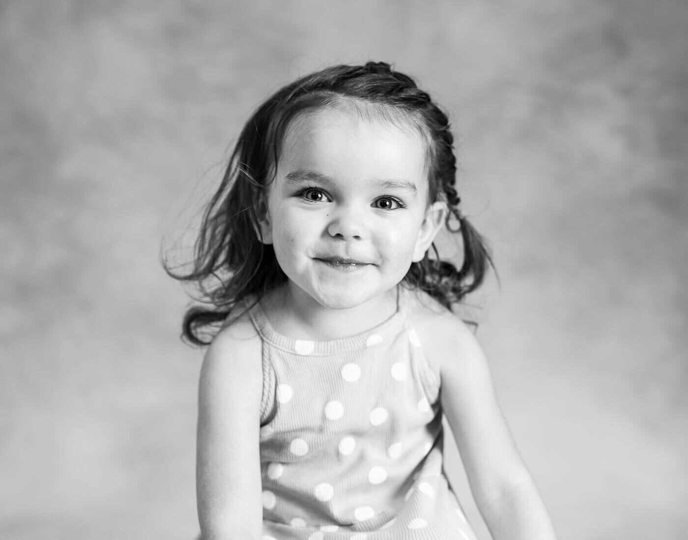A child smirks in a black and white photo.