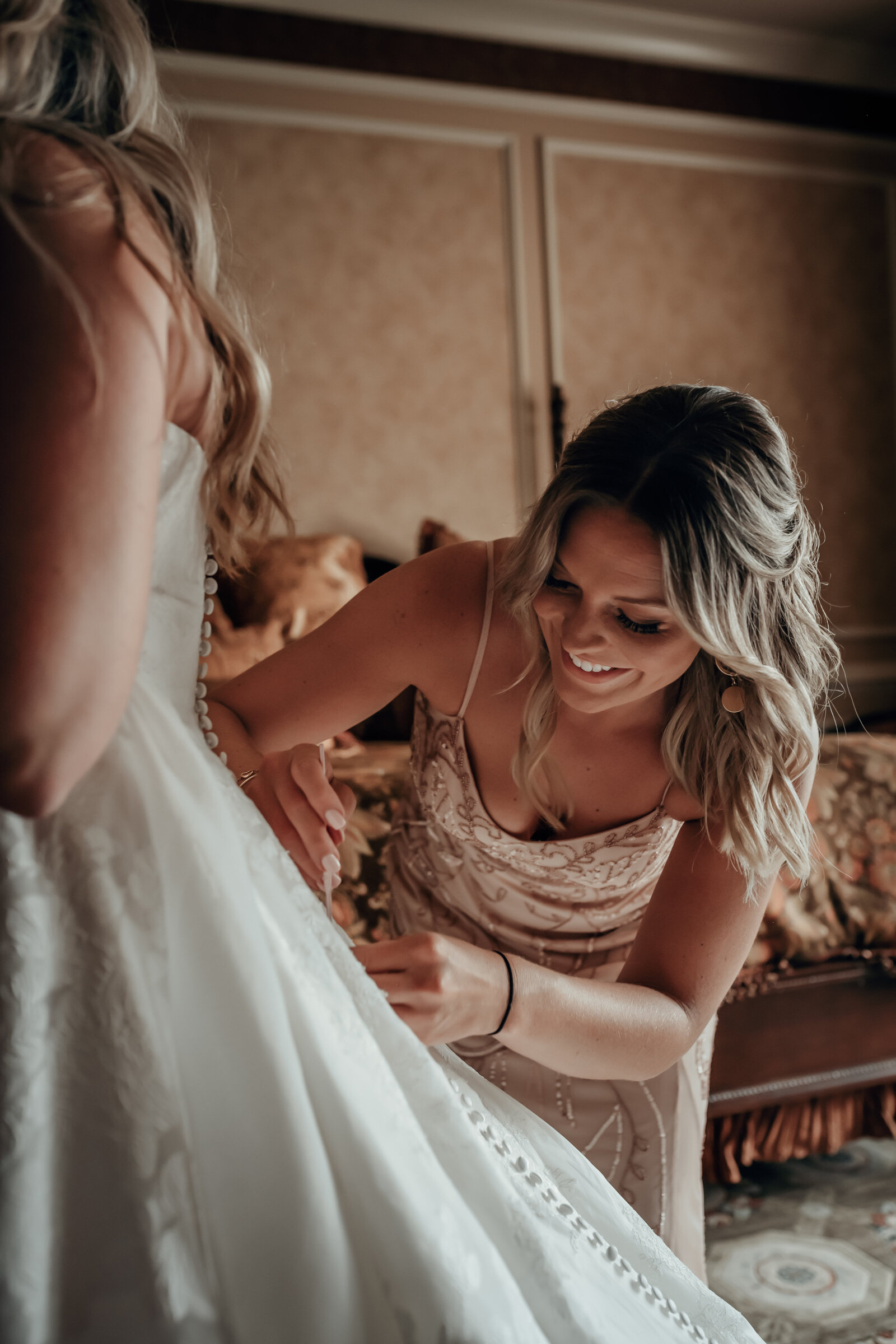 An intimate wedding with a bridesmaid helping the bride get into her wedding dress