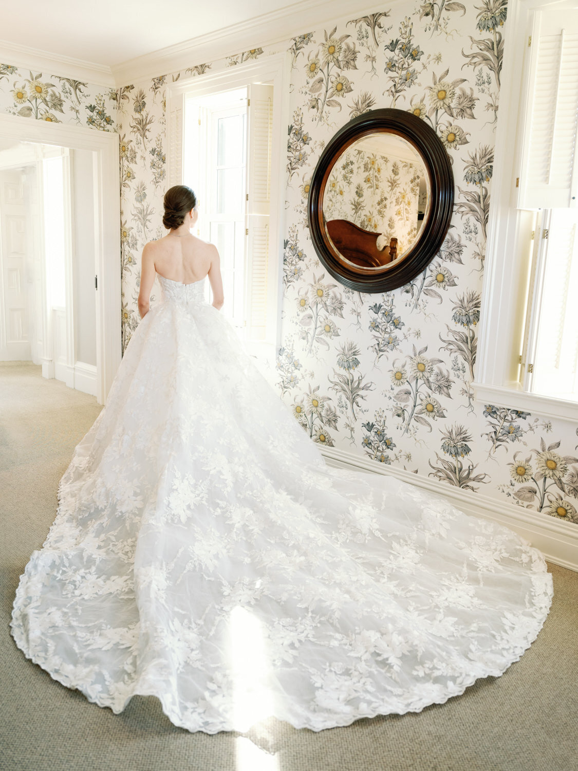 Bride in wedding gown looking at the window of a luxury resort.