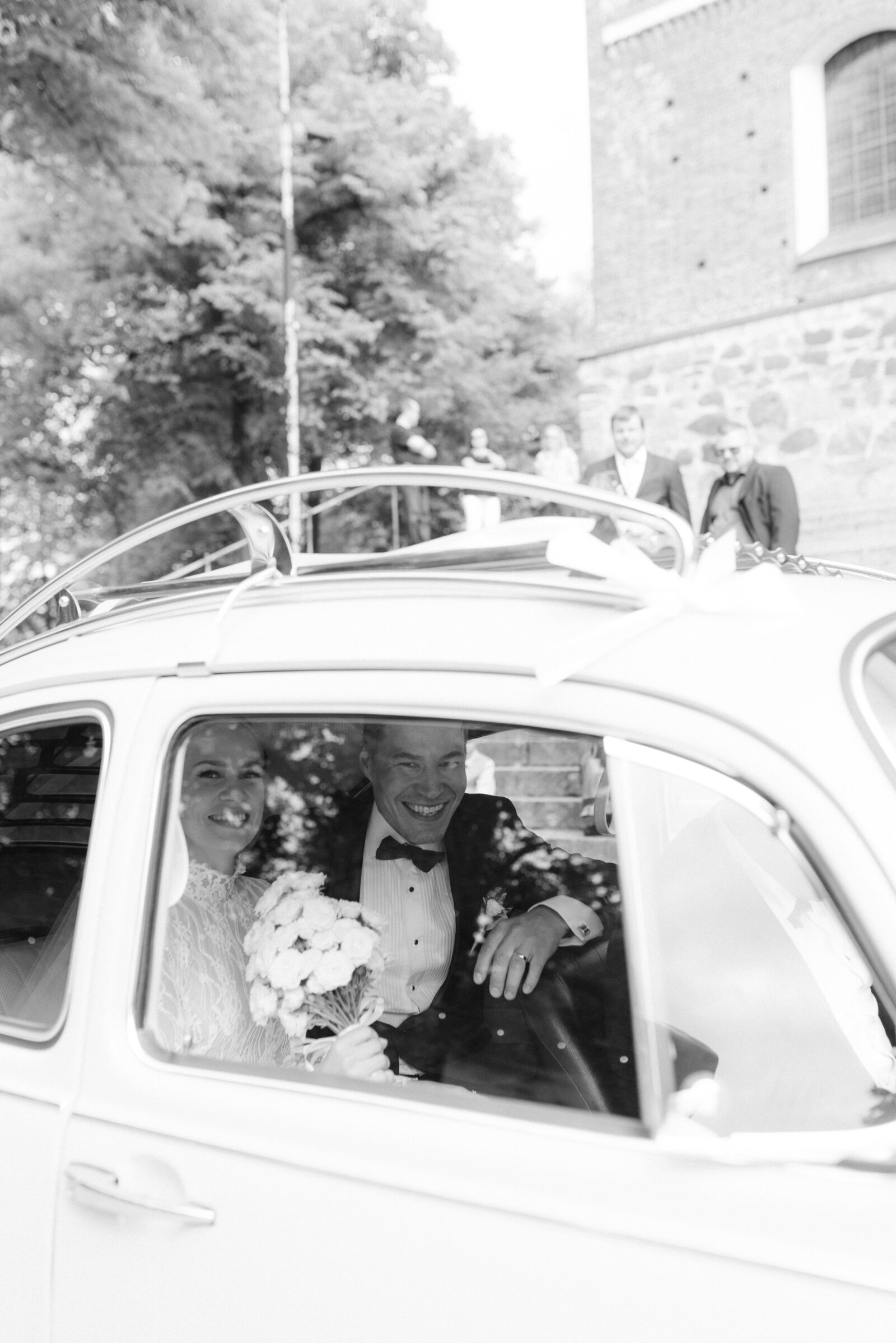 Wedding couple sitting on the car after the ceremony. Image by wedding photographer Hannika Gabrielsson.