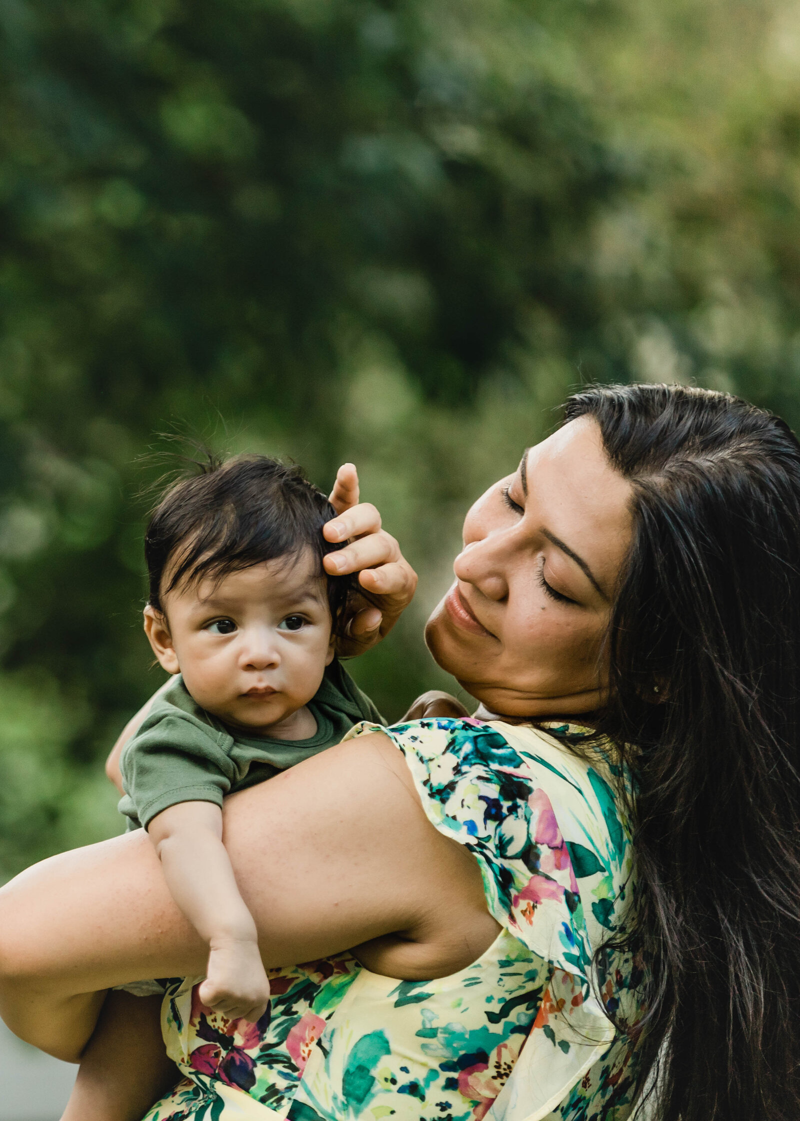 Mother brushing baby's boy's hair out of eyes