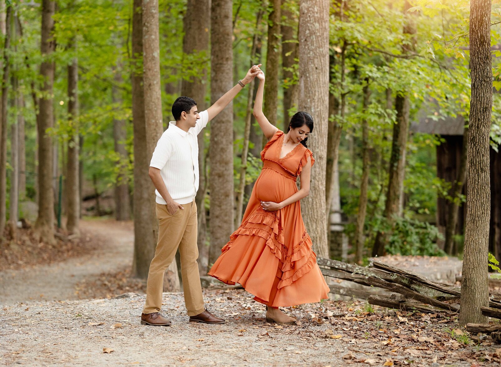 Dad twirling pregnant Mom and dancing in the woods. Photo taken at an Atlanta outdoor family photo location.