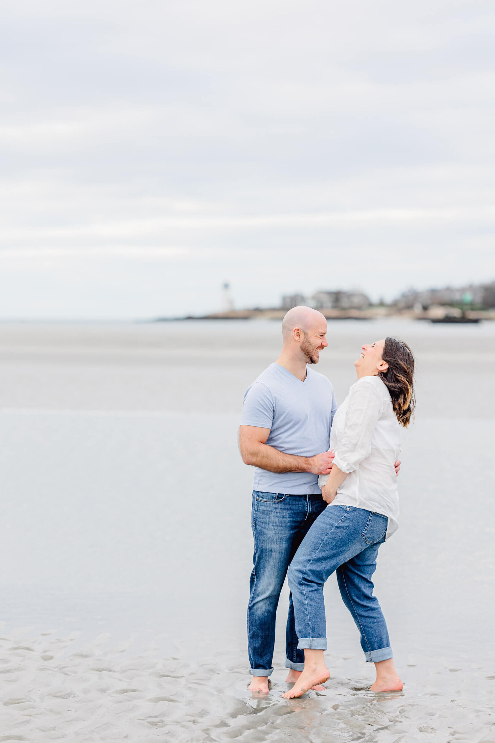 Man and his wife laugh on the sand in front of the ocean