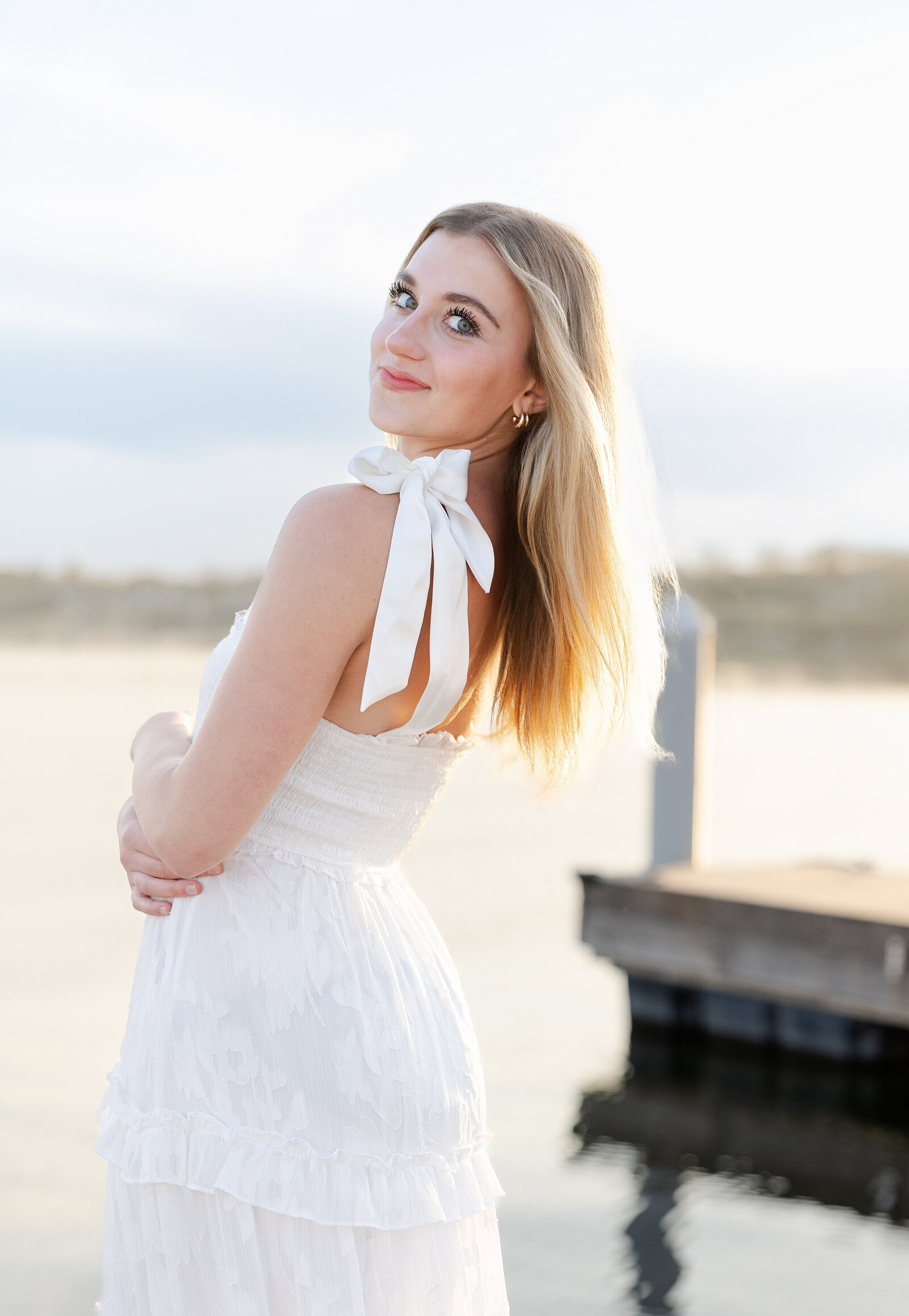senior girl looks over shoulder on a wayzata dock for her wayzata senior pictures with angela watts.
