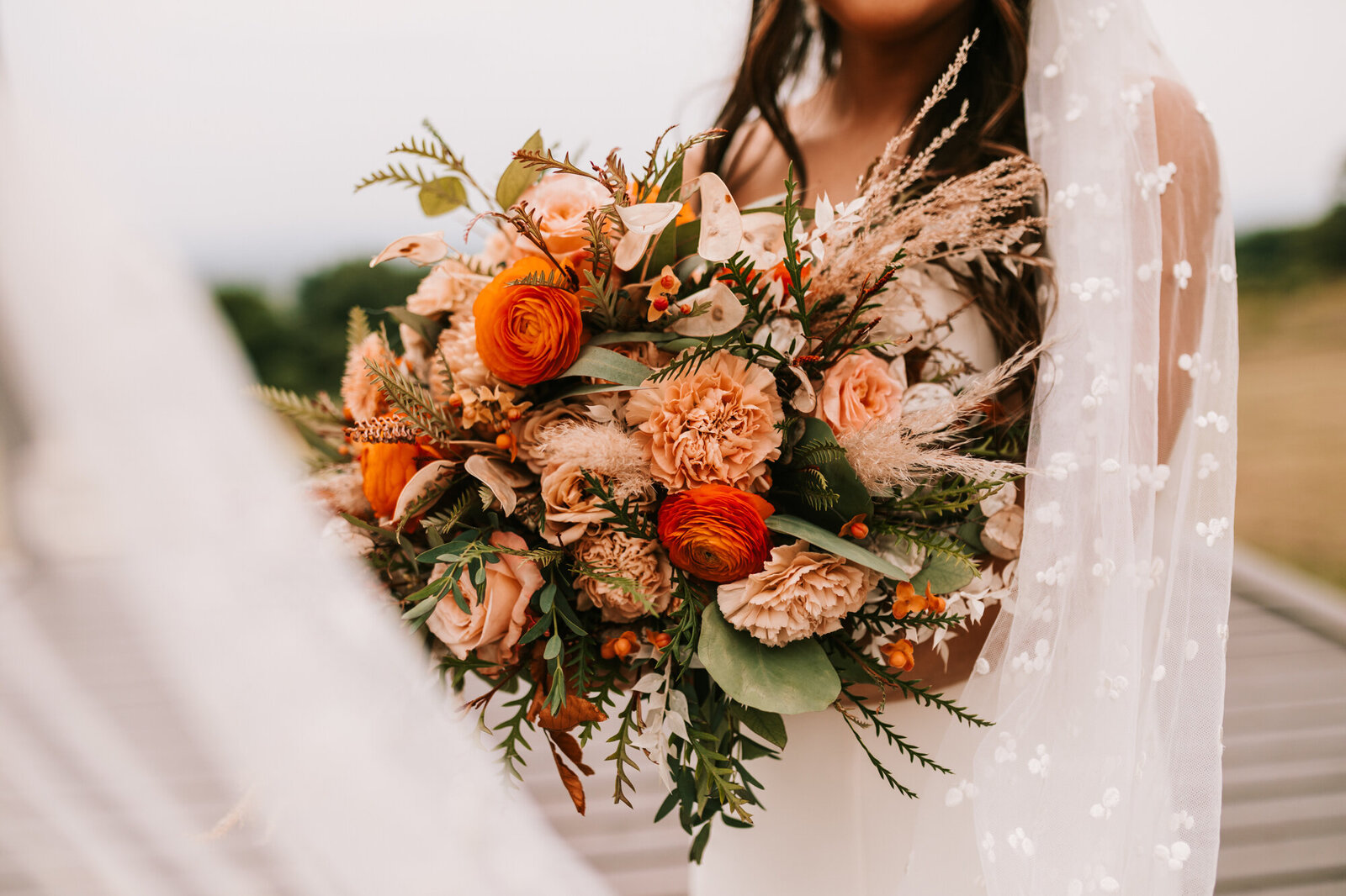 bride holding flowers with veil blowing in the wind