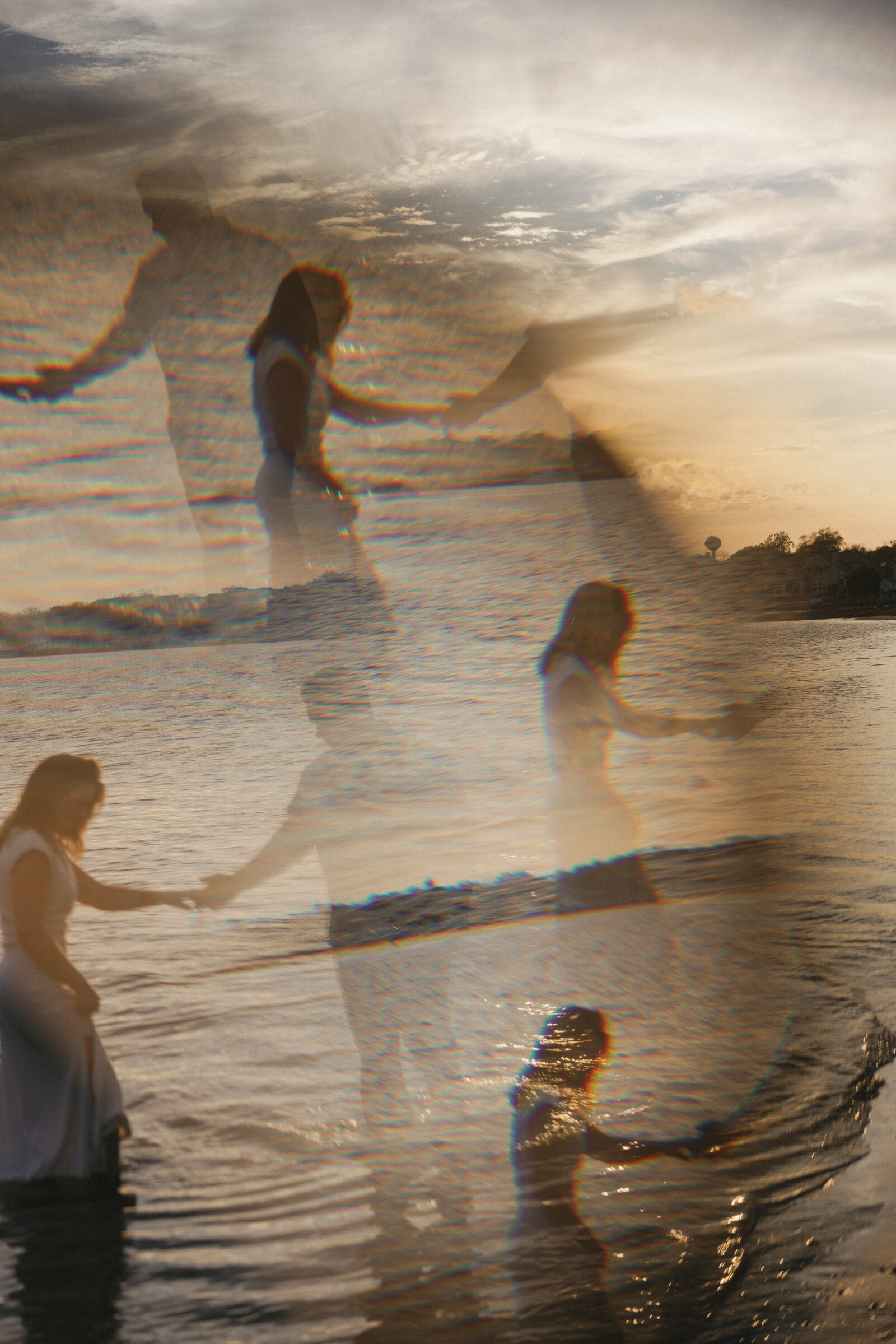 Prism photo of couple holding hands splashing their feet in water at coastal engagement session during sunset