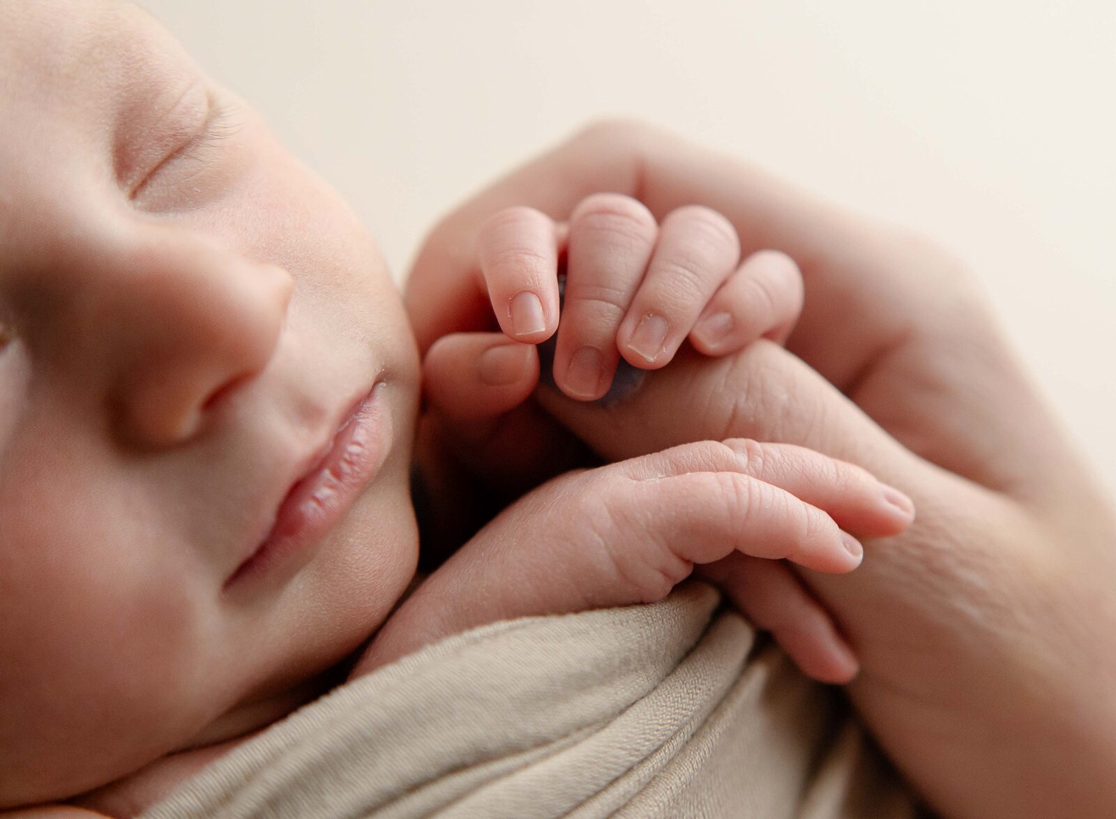 Baby sleeping and holding mom's thumb. Marietta newborn photographer took photo at Jenni Nikki's studio.